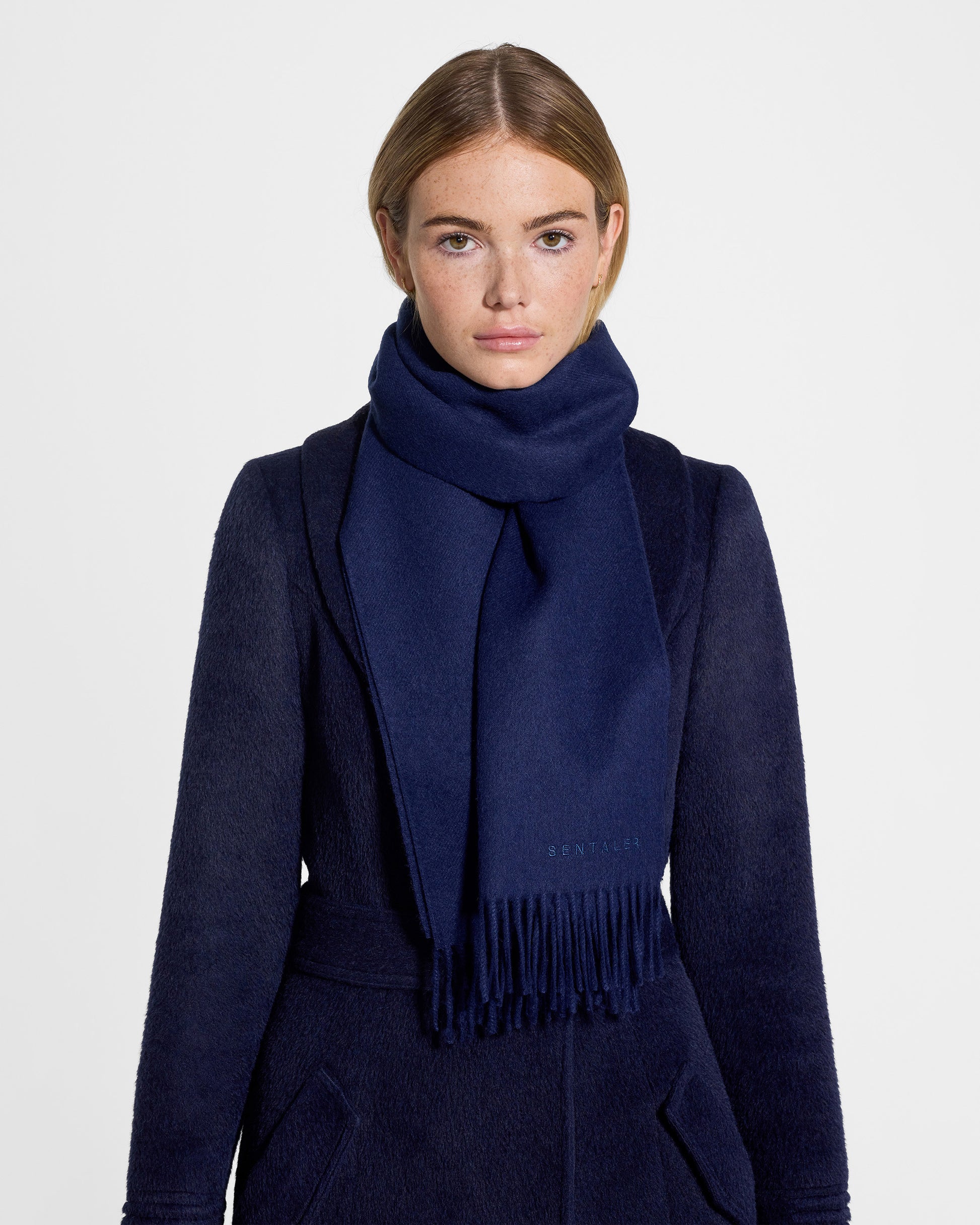 Front close up view of model wearing Sentaler's adult Navy classic scarf, made of baby alpaca yarn. 