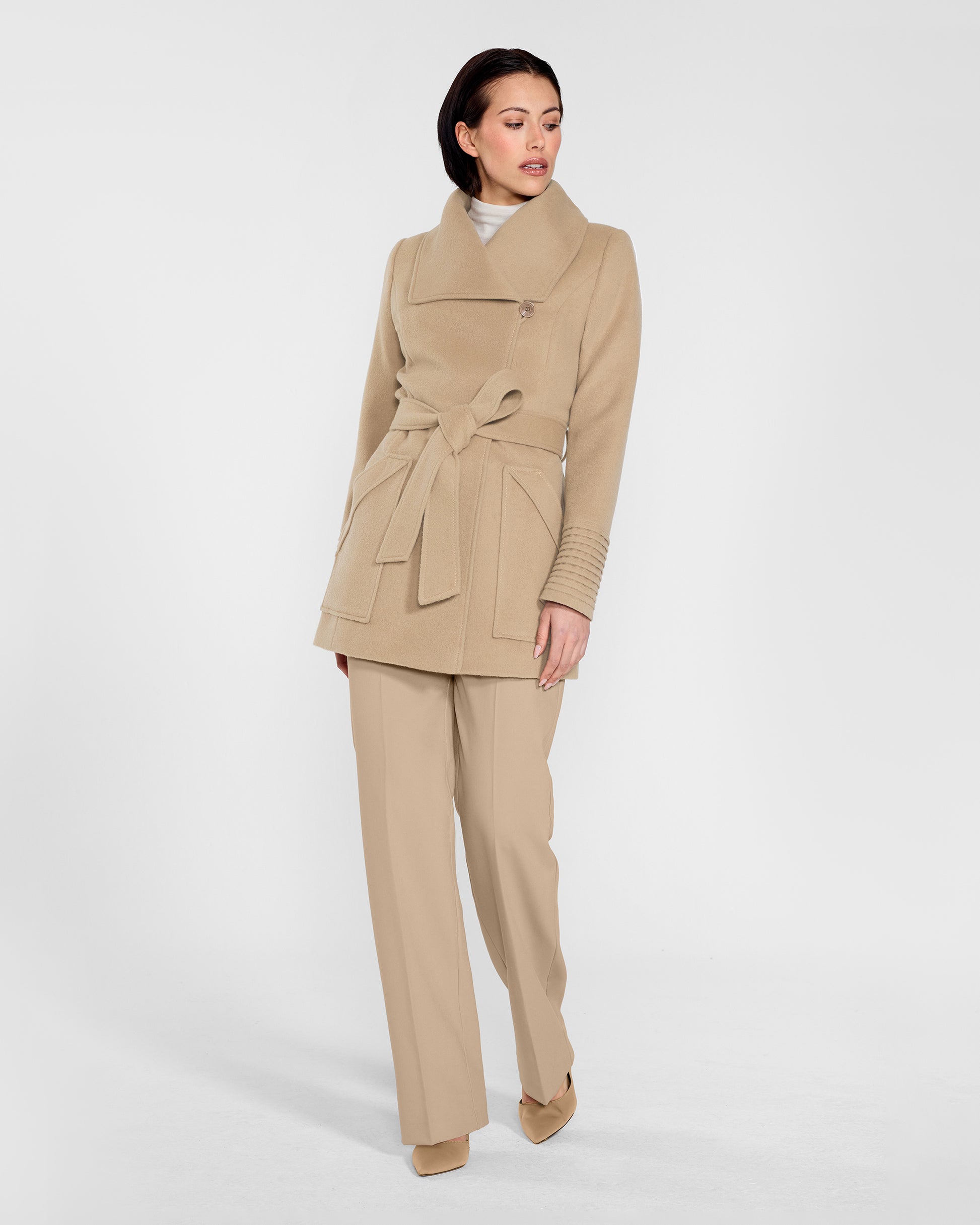 Front view of model wearing a Sentaler camel cropped wrap coat made of baby alpaca wool, with a wide collar, worn belted.