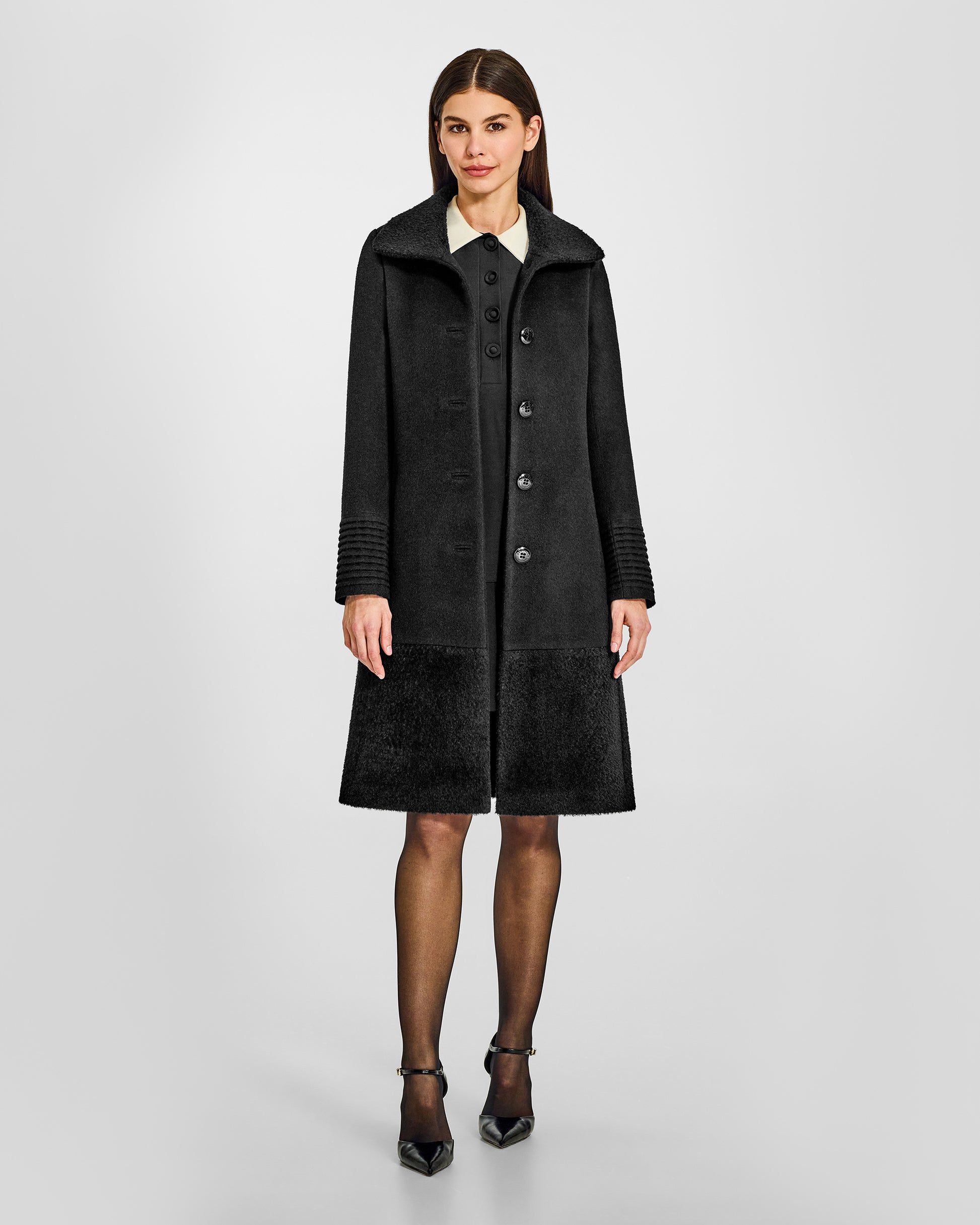 Front view of model wearing a Sentaler black A-line coat made of baby alpaca wool, with an empire waist, worn open.