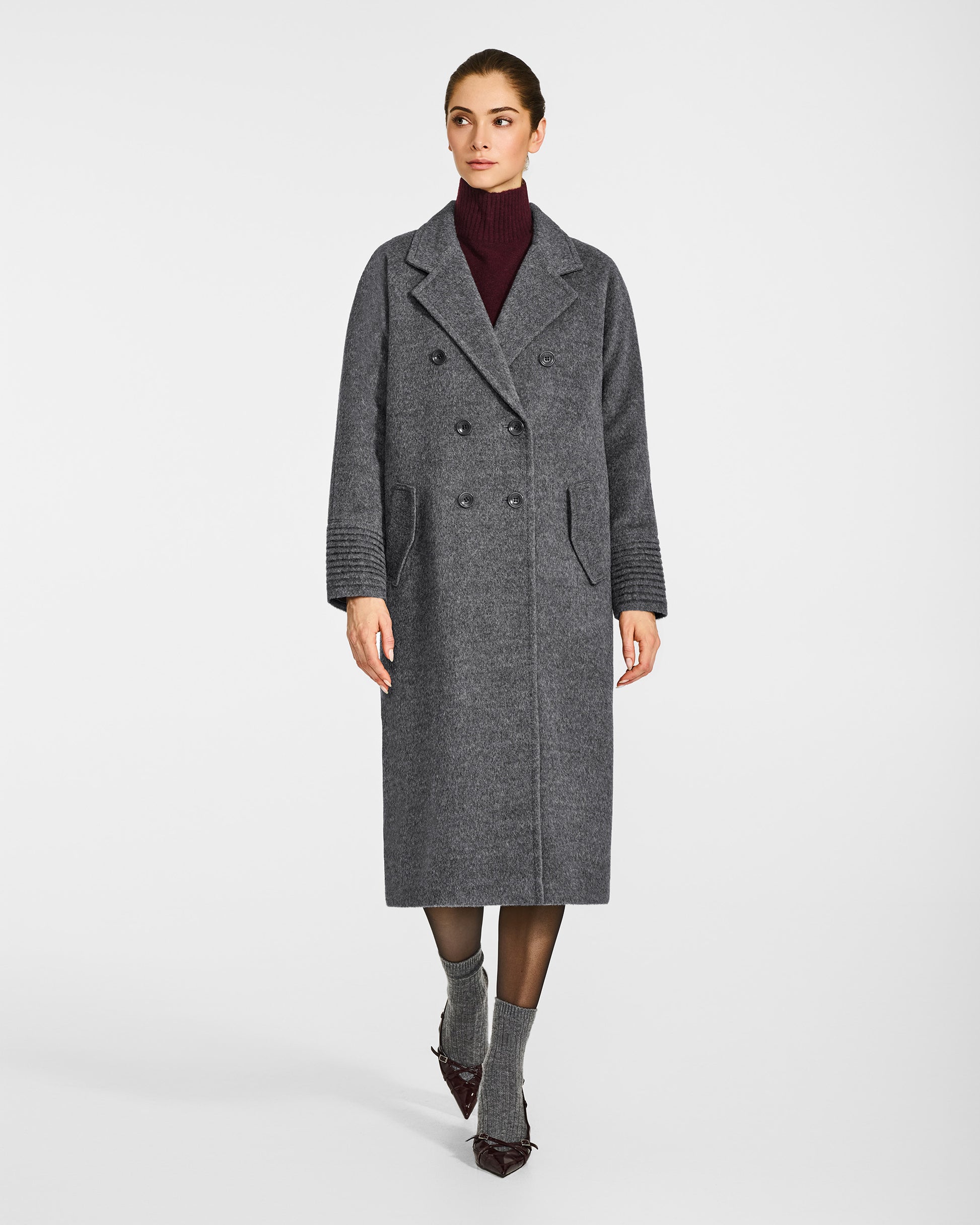 Front view of model in Sentaler grey mélange double breasted coat with notched collar in baby alpaca wool, buttoned.