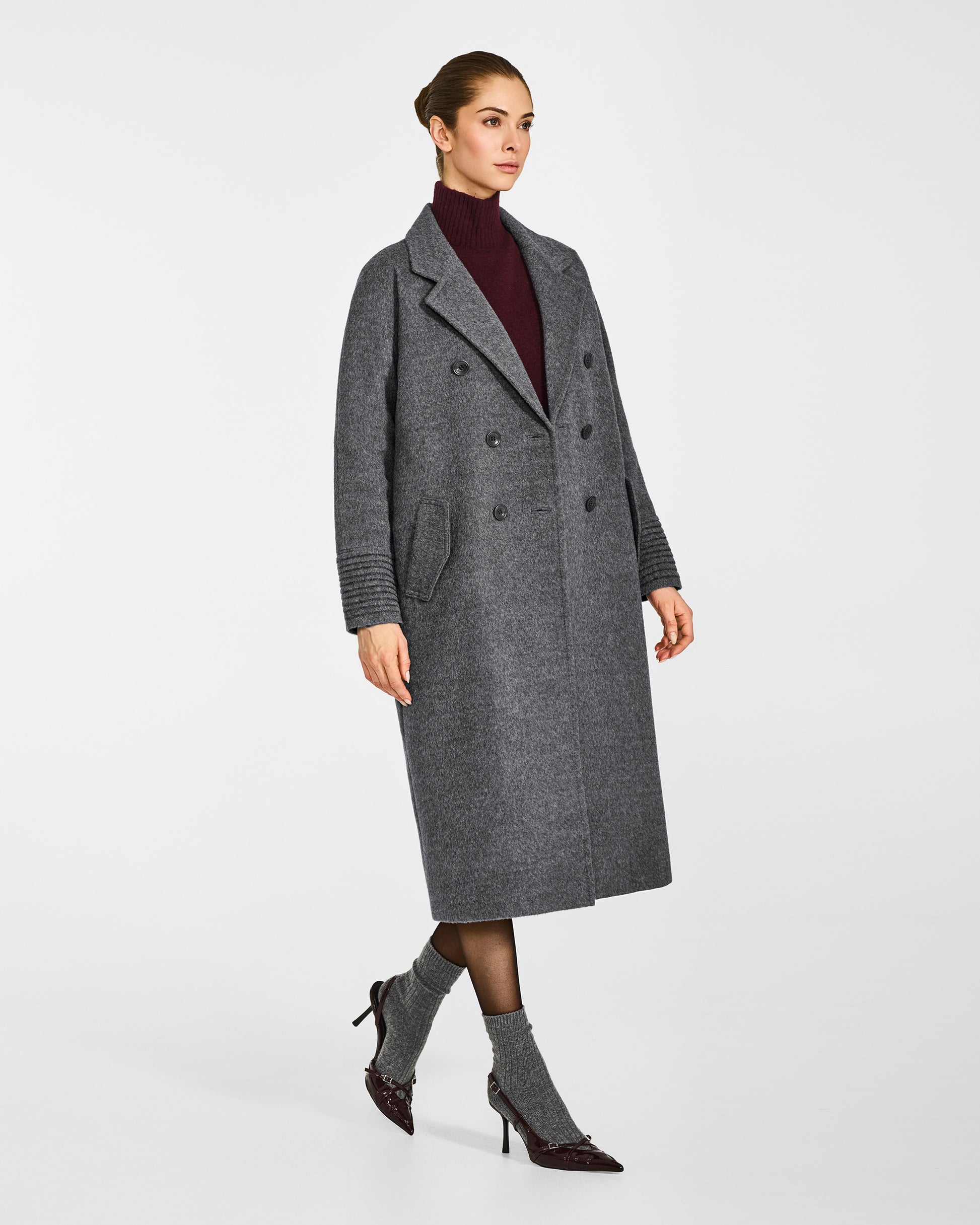 Side view of model in Sentaler grey mélange double breasted coat with notched collar in baby alpaca wool, open.