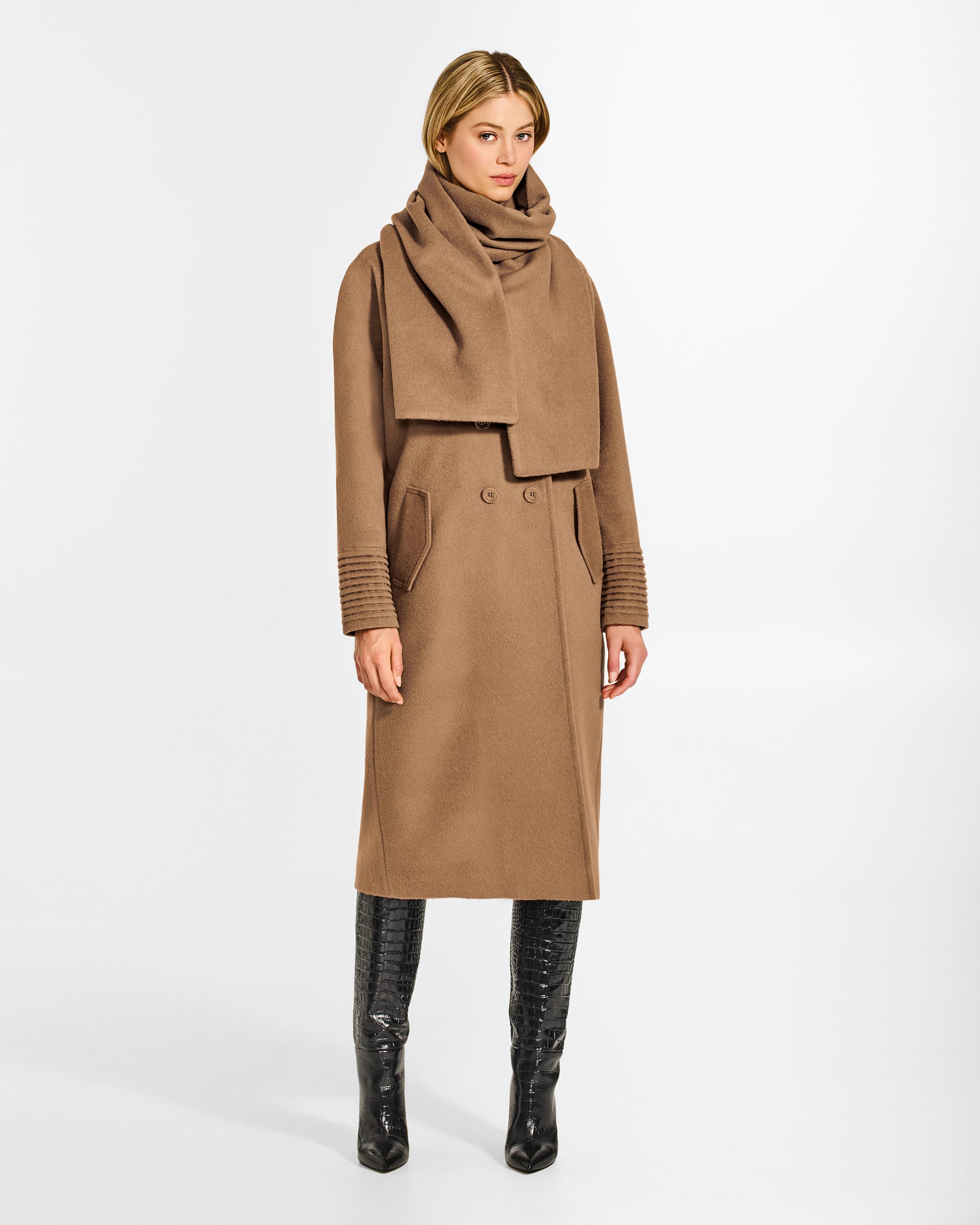 Side view of model wearing a Sentaler dark camel double breasted coat made of baby alpaca wool with a notched collar, worn with fabric scarf, buttoned. 