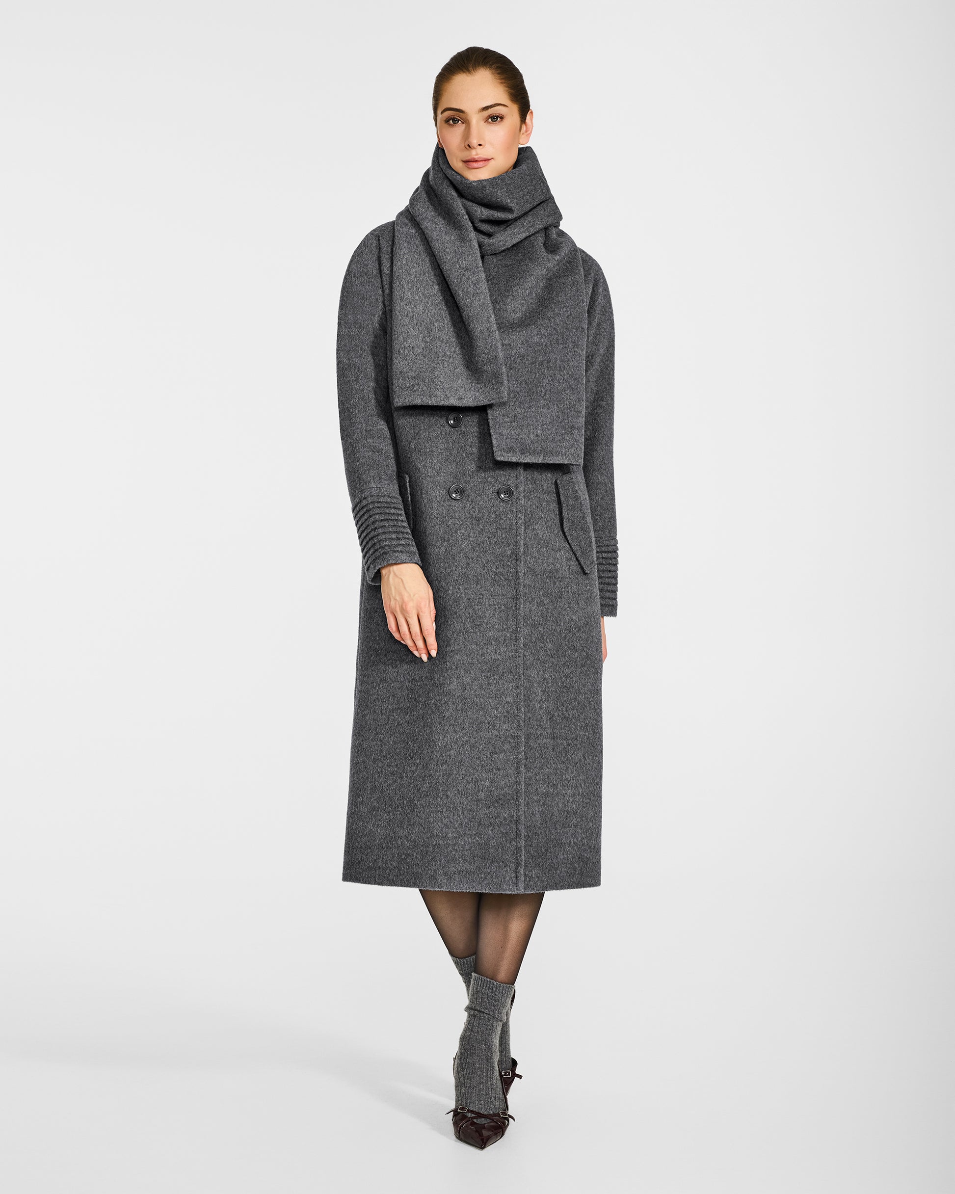 Front view of model wearing a Sentaler  grey mélange double breasted coat made of baby alpaca wool with a notched collar, worn with fabric scarf, buttoned.