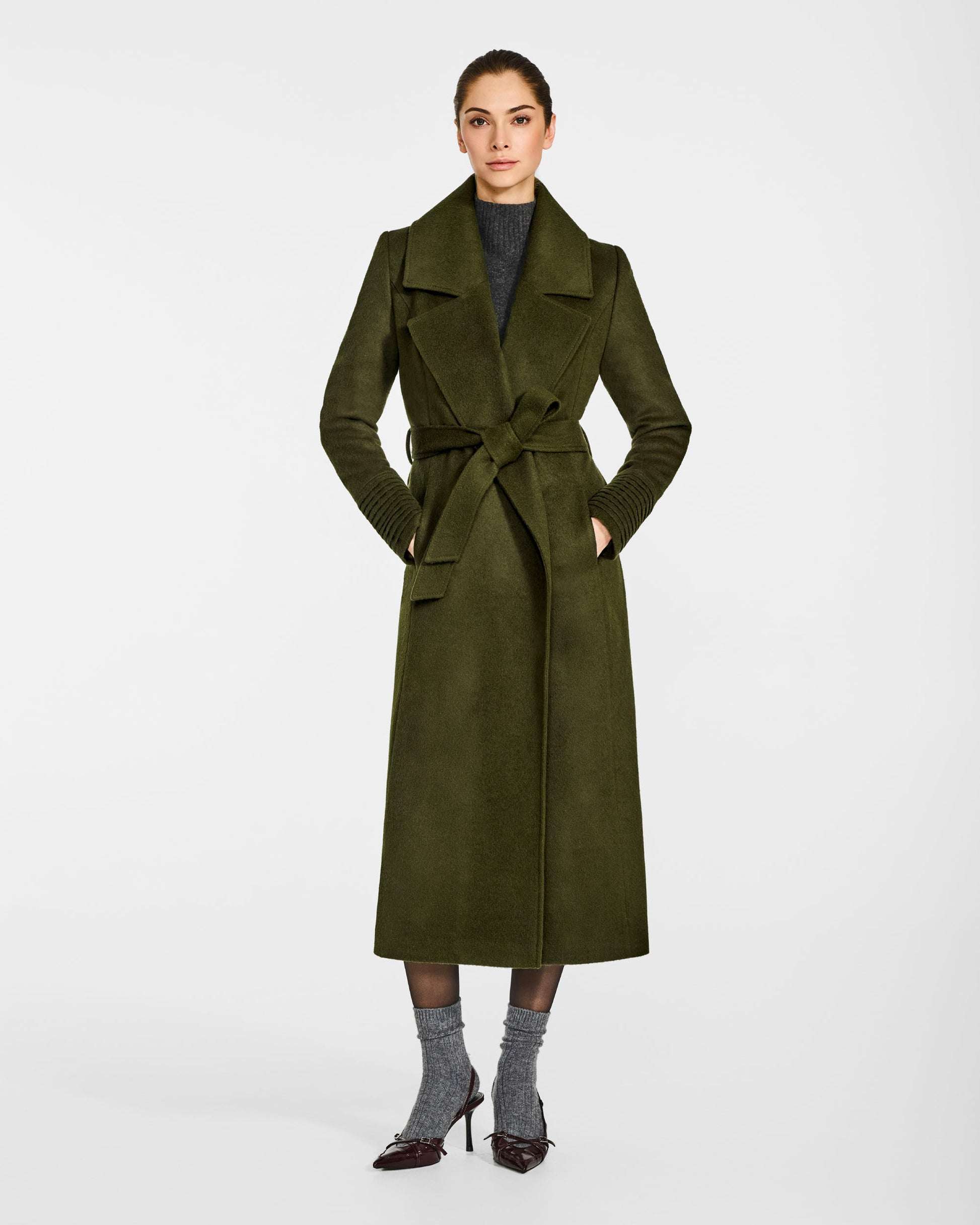 Front view of model wearing a SENTALER long olive green wrap coat made of baby alpaca wool, with a large notched collar, worn belted.