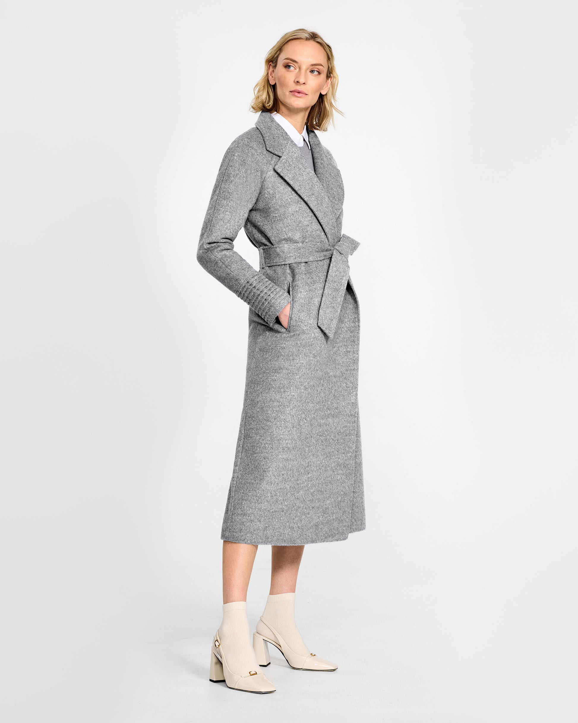 Side view of model wearing a SENTALER long shale grey wrap coat made of baby alpaca wool, with raglan sleeves, worn belted.