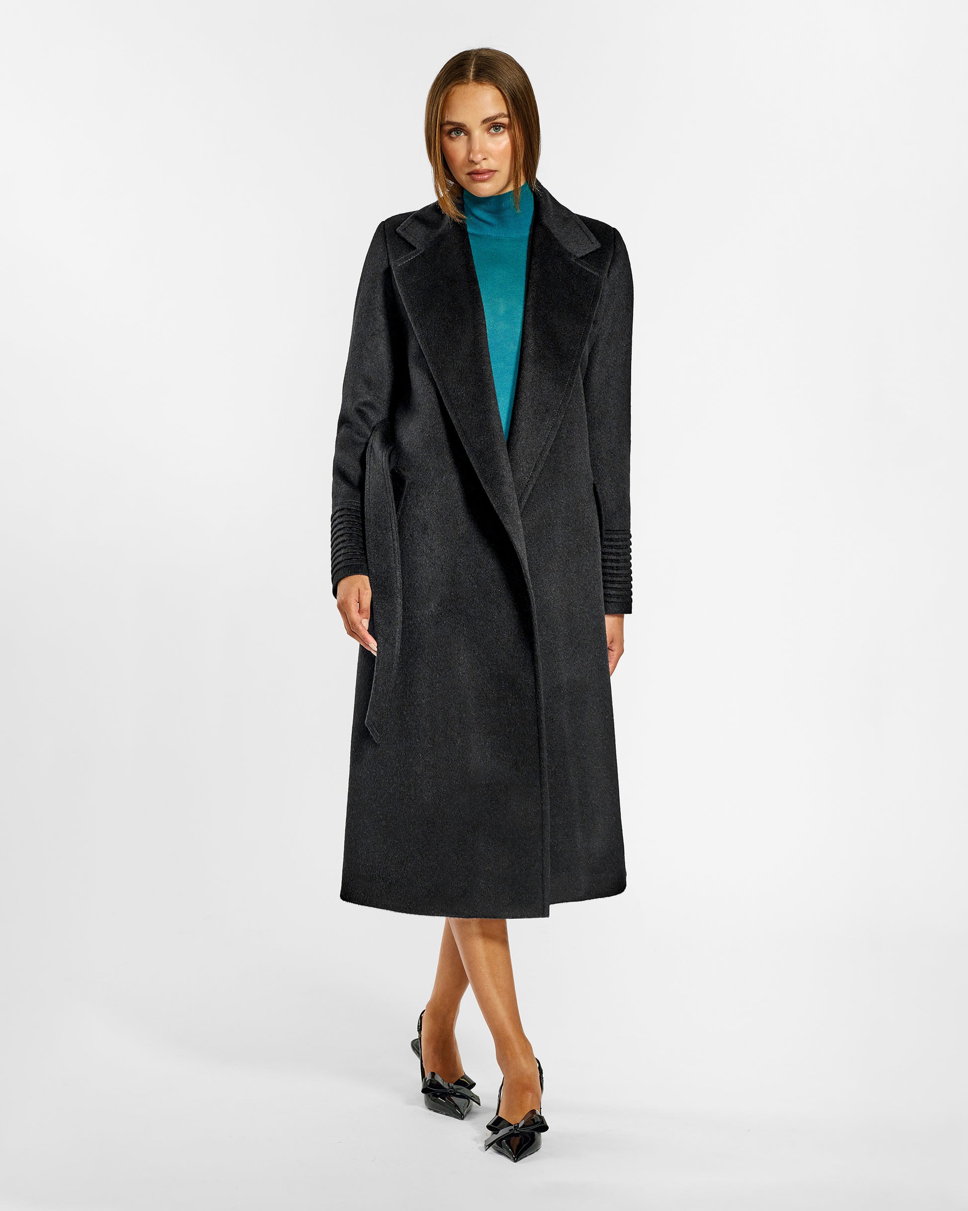 Front view of model wearing a Sentaler long black wrap coat made of baby alpaca wool, with a notched collar, worn open.