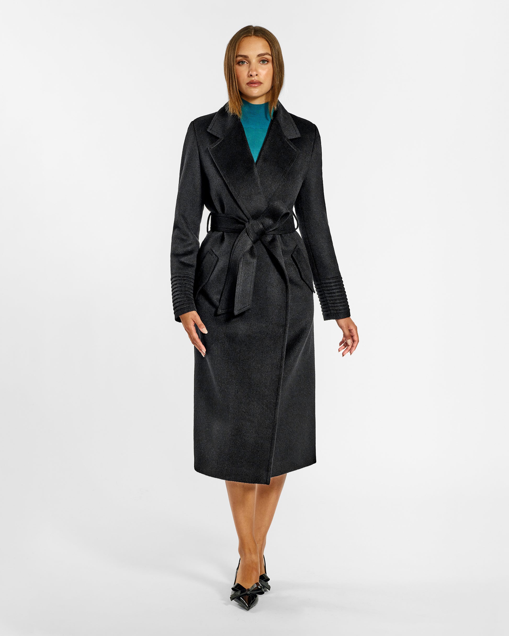 Front view of model wearing a Sentaler long black wrap coat made of baby alpaca wool, with a notched collar, worn belted.