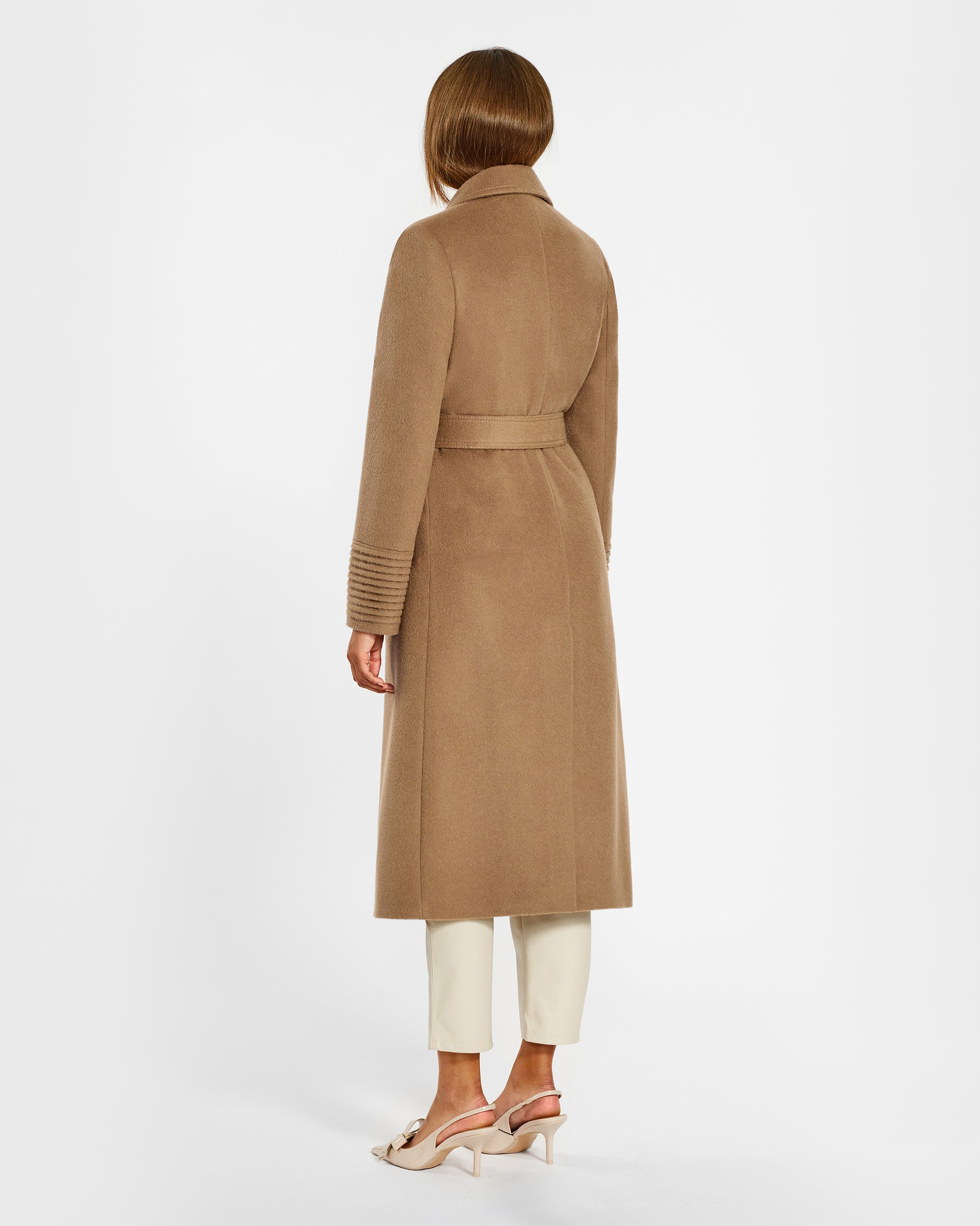 Back view of model wearing a Sentaler long dark camel wrap coat made of baby alpaca wool, with a notched collar, worn belted.