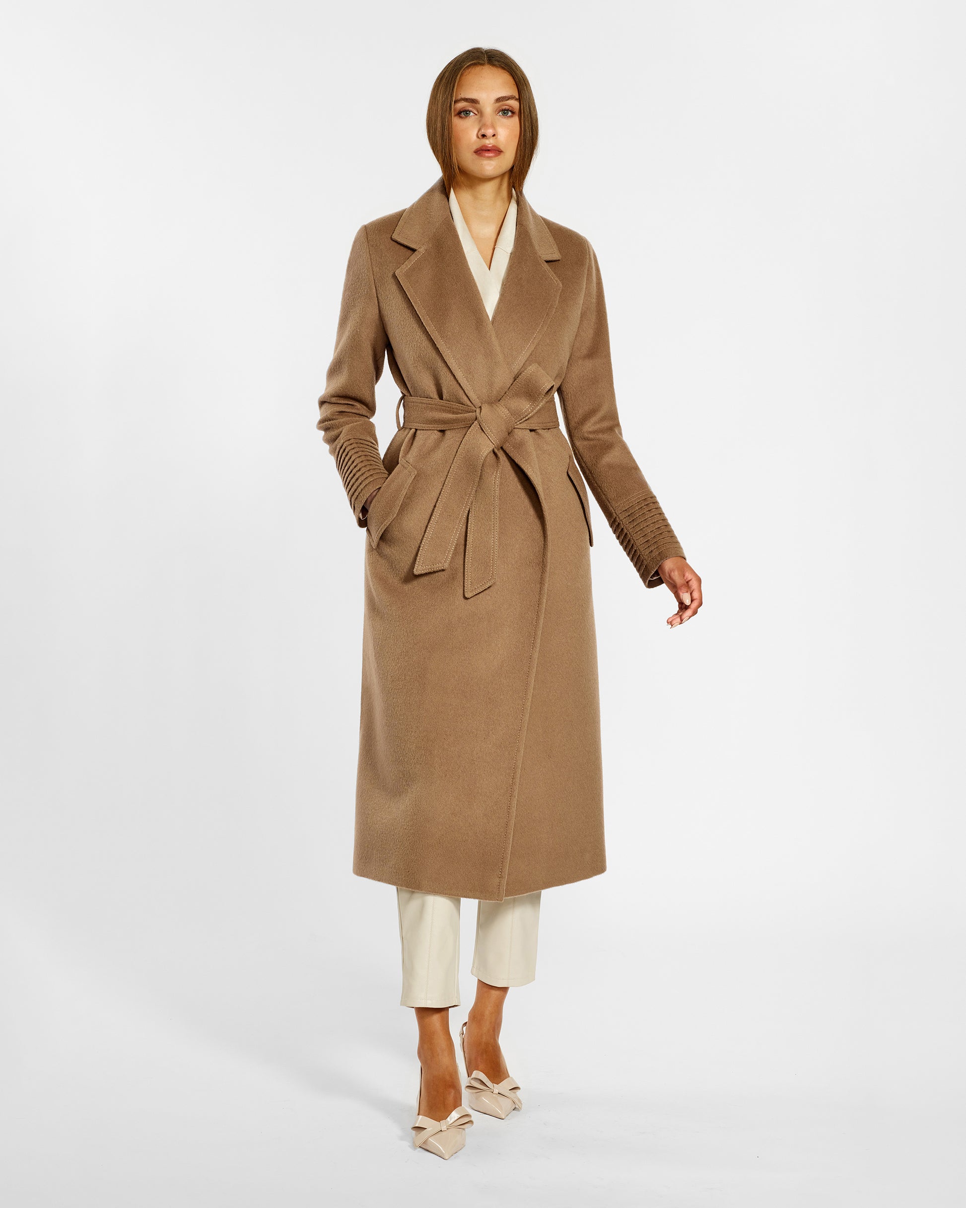 Front view of model wearing a Sentaler long dark camel wrap coat made of baby alpaca wool, with a notched collar, worn belted.