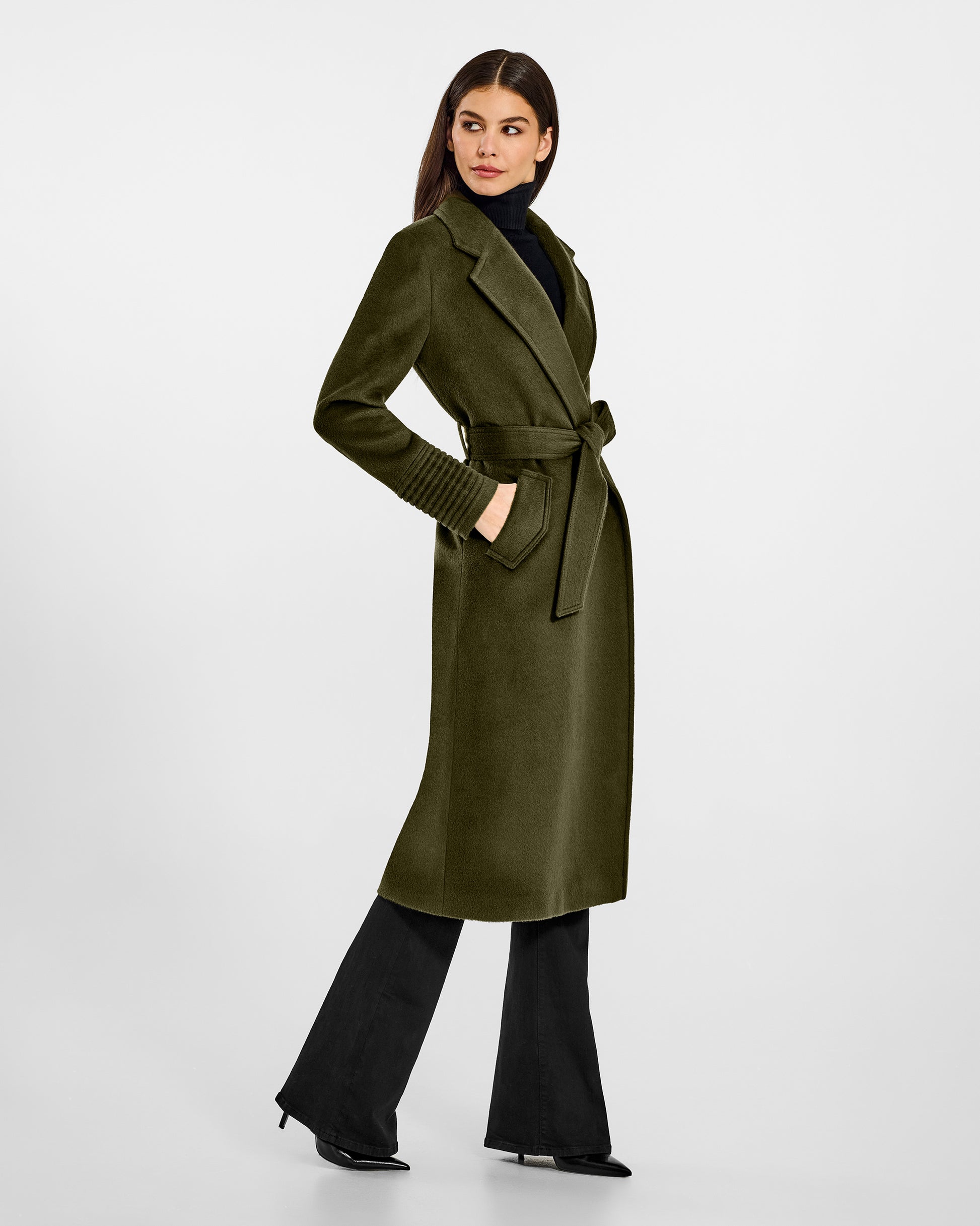 Side view of model wearing a Sentaler long olive green wrap coat made of baby alpaca wool, with a notched collar, worn belted.