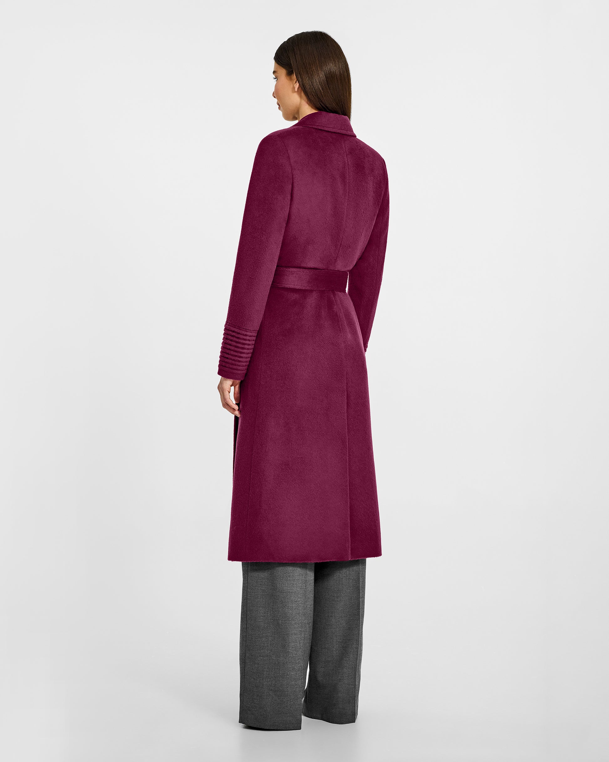 Back view of model wearing a Sentaler long plum berry purple wrap coat made of baby alpaca wool, with a notched collar, worn belted.