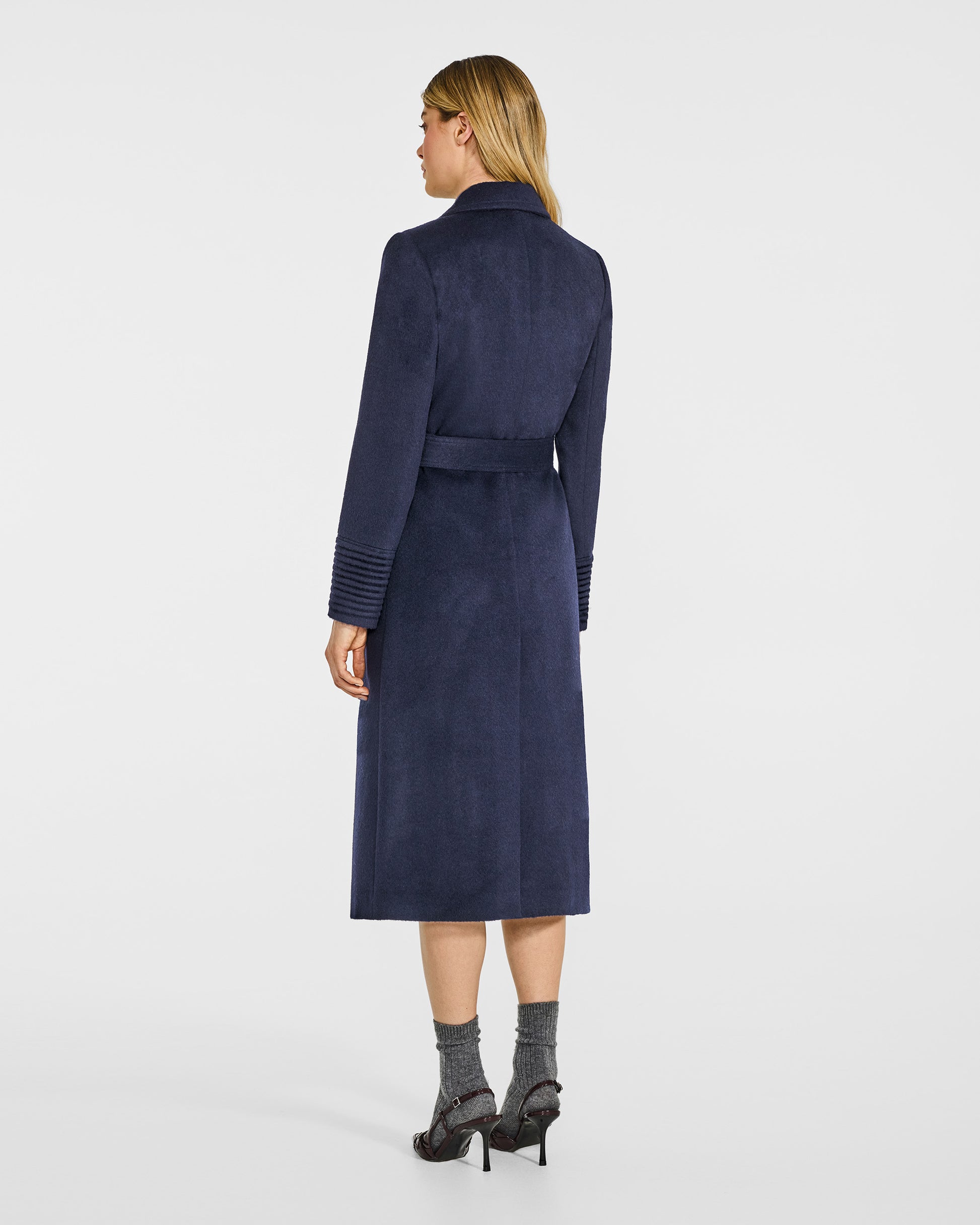 Back view of model in Sentaler long deep navy wrap coat with notched collar in baby alpaca wool, belted.