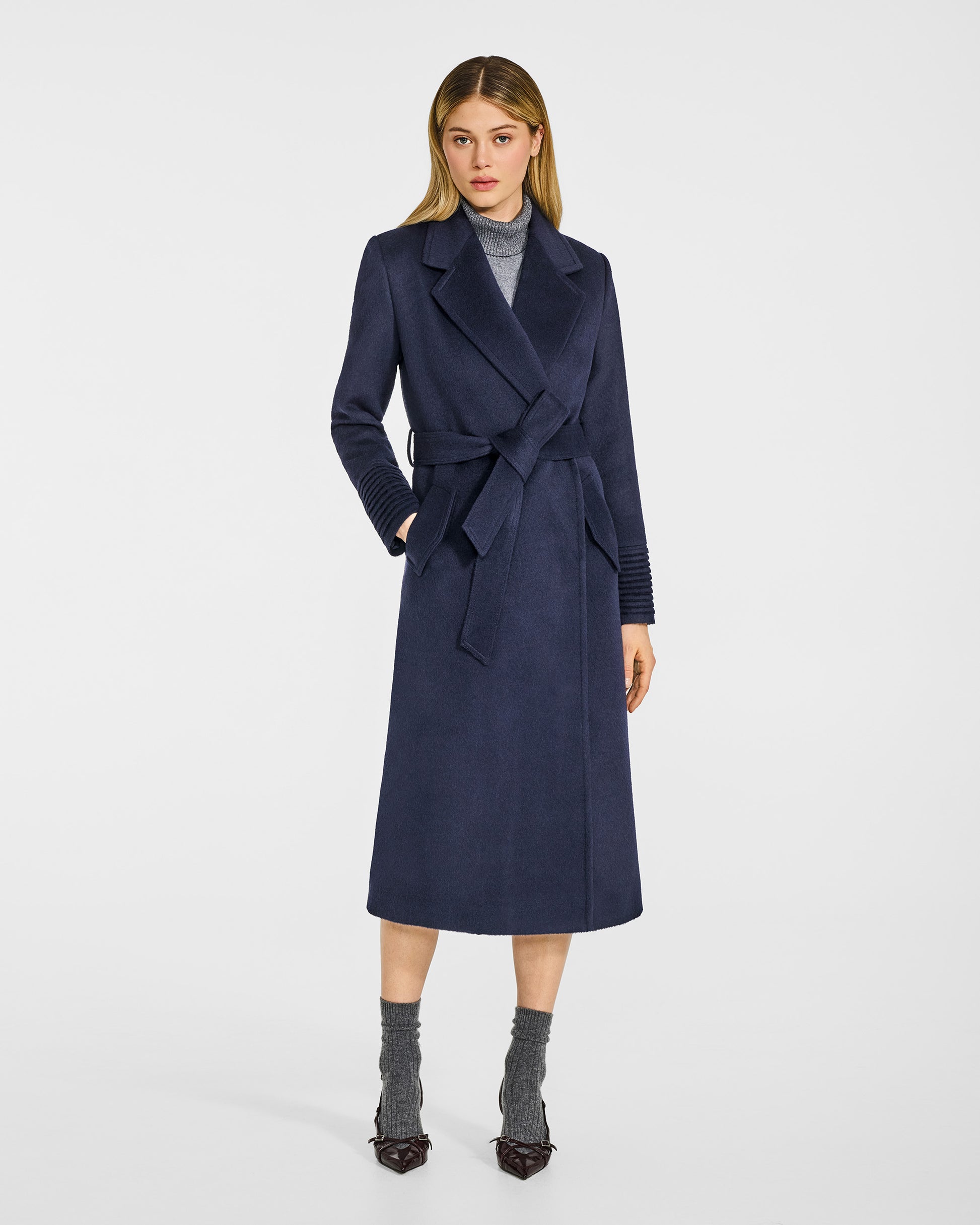 Front view of model in Sentaler long deep navy wrap coat with notched collar in baby alpaca wool, belted.