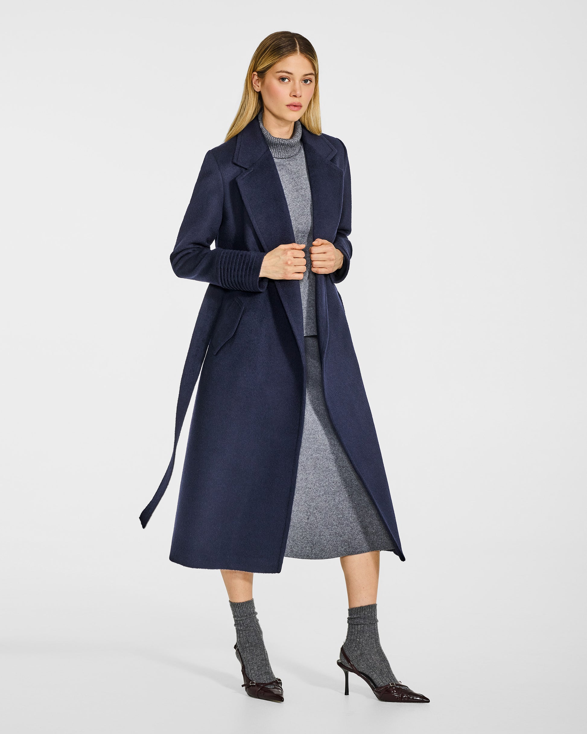 Side view of model in Sentaler long deep navy wrap coat with notched collar in baby alpaca wool, open.