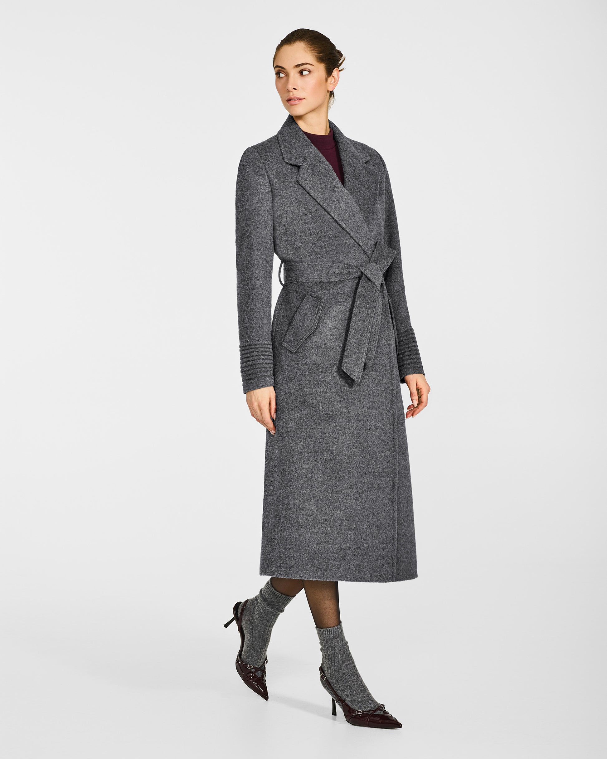 Side view of model wearing a Sentaler long grey mélange wrap coat made of baby alpaca wool, with a notched collar, worn belted.