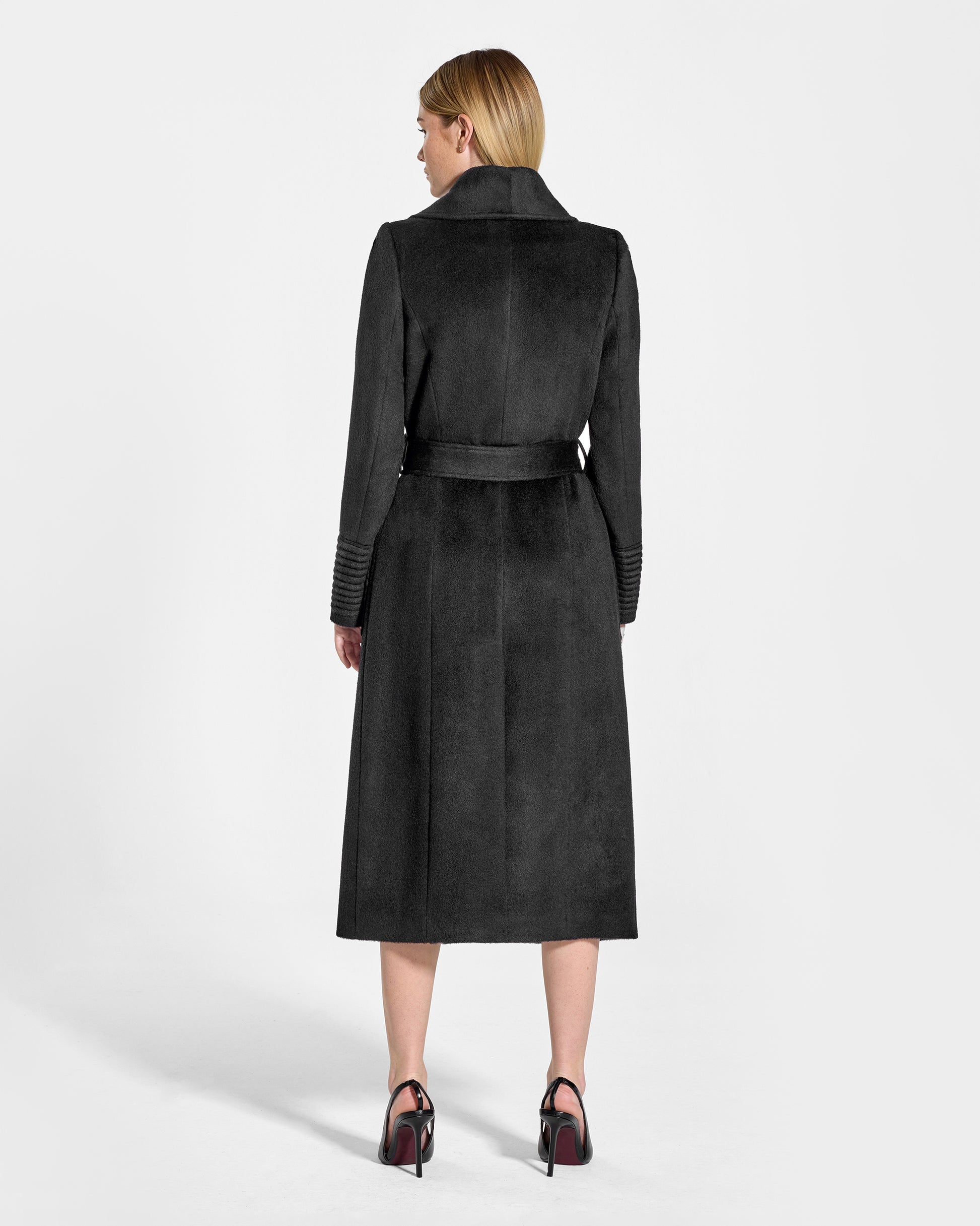 Back view of model wearing a Sentaler black long wrap coat made of baby alpaca wool, with a wide collar, worn belted.
