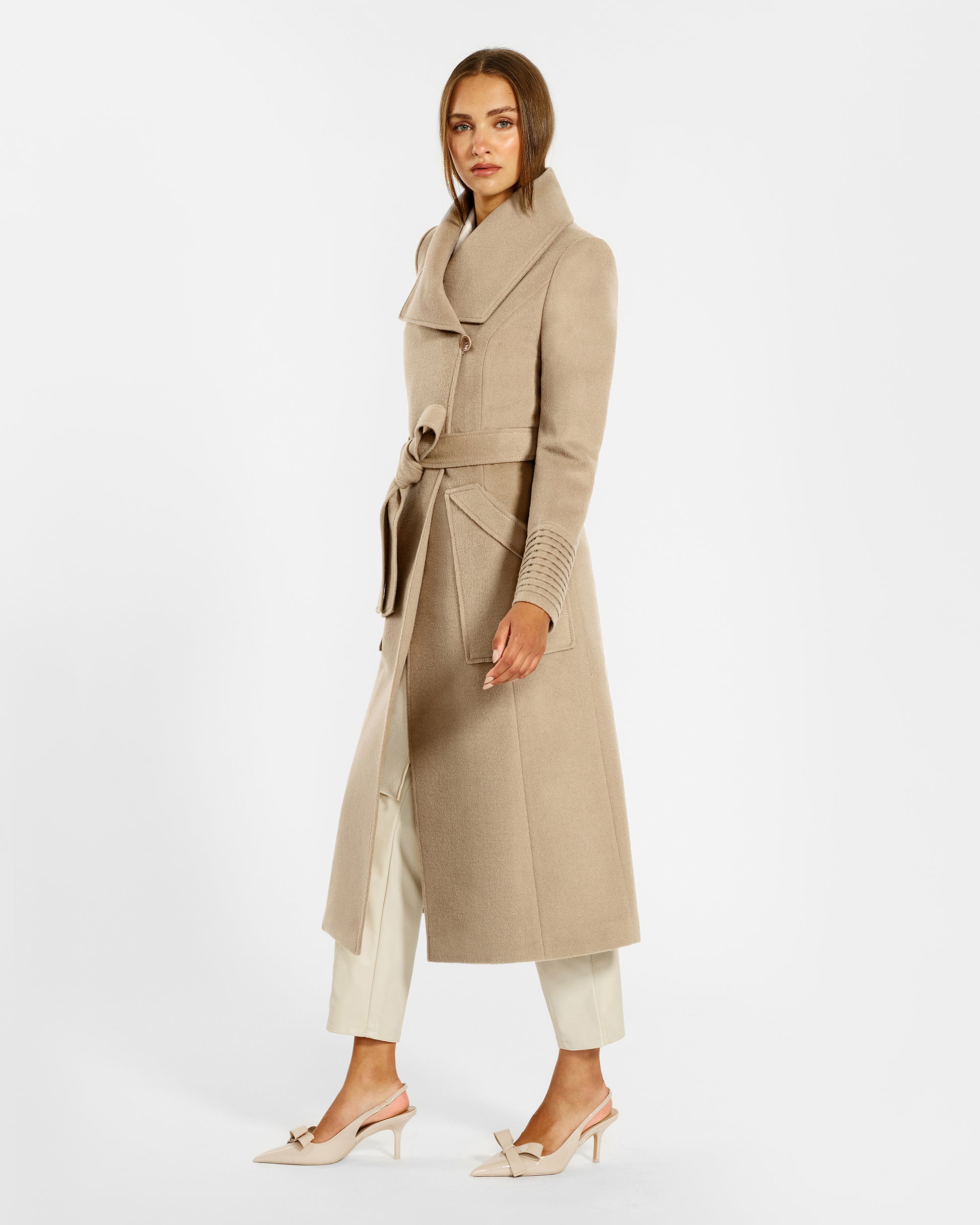 Side view of model wearing a Sentaler camel long wrap coat made of baby alpaca wool, with a wide collar, worn belted.