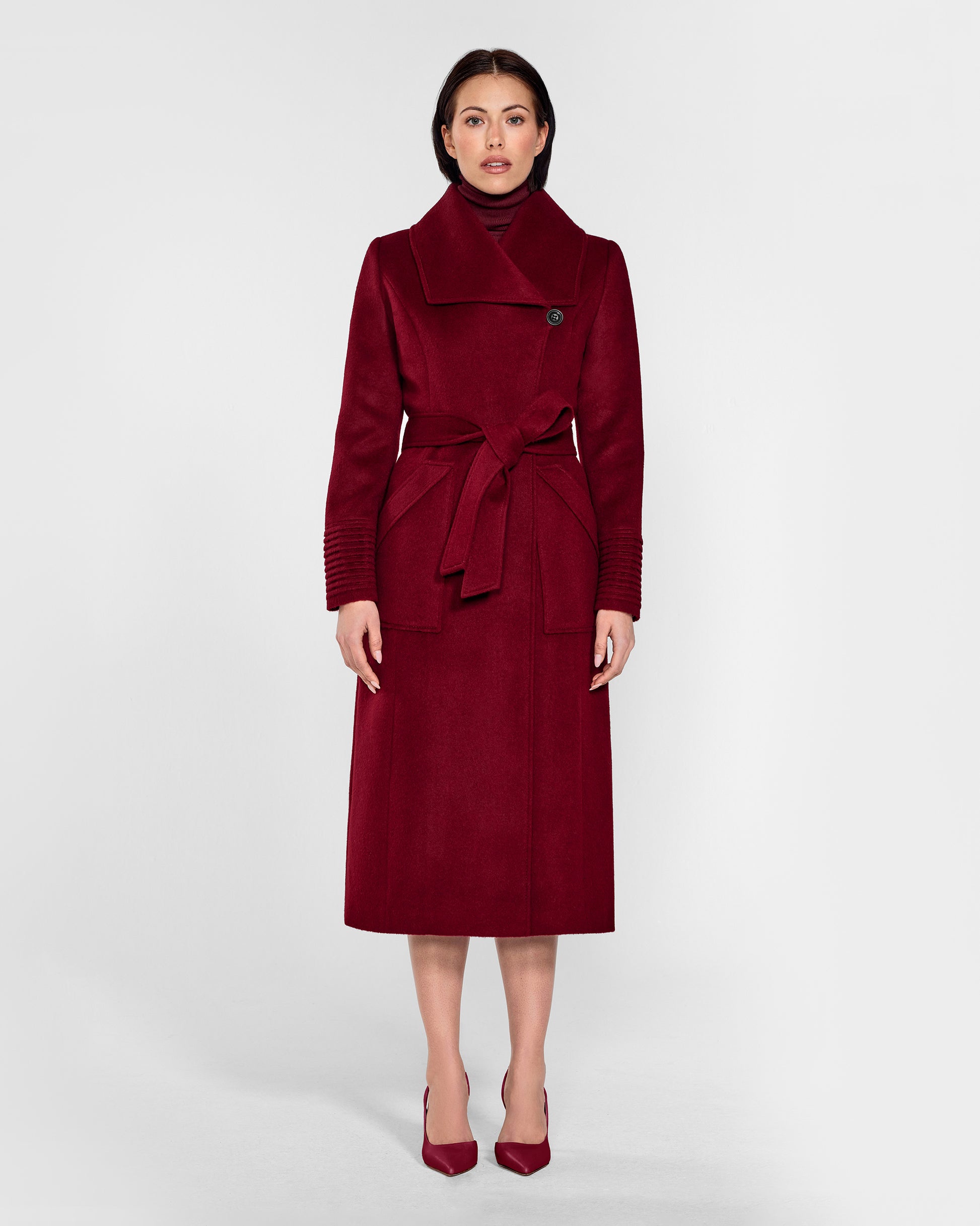 Front view of model wearing a Sentaler garnet red long wrap coat made of baby alpaca wool, with a wide collar, worn belted.