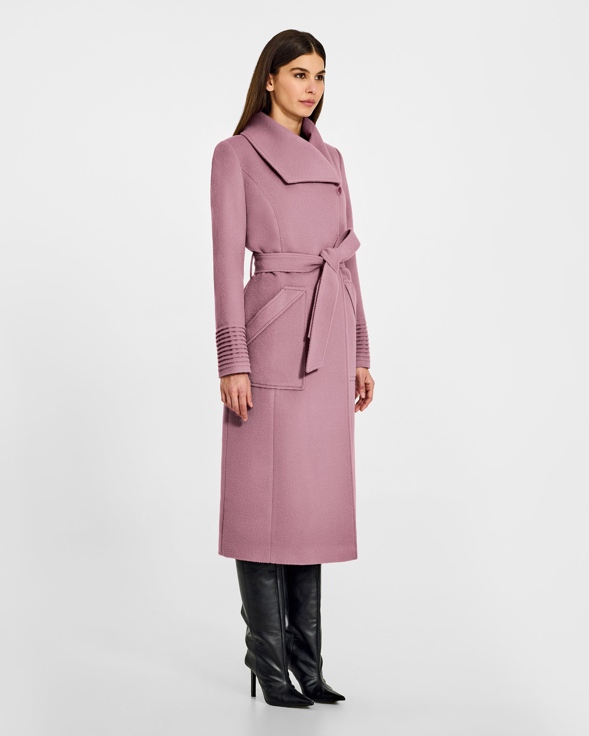 Side view of model wearing a Sentaler peony pink long wrap coat made of baby alpaca wool, with a wide collar, worn belted.
