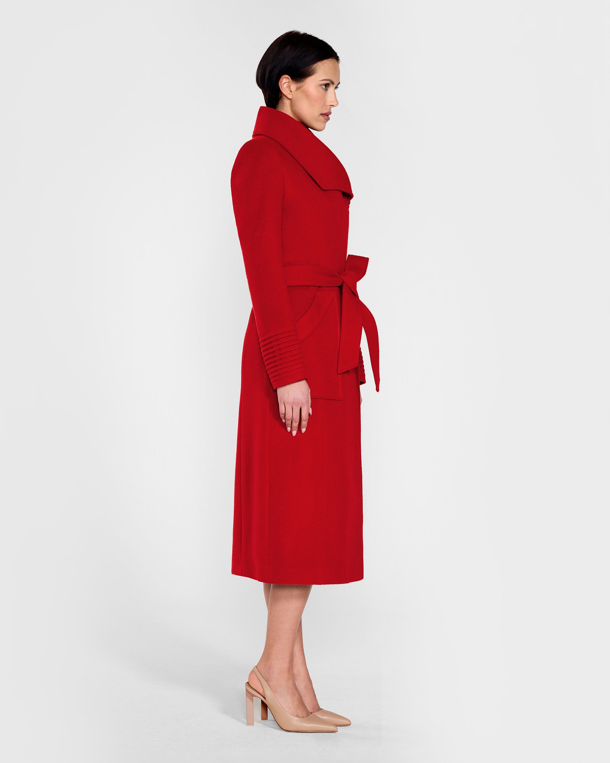 Side view of model wearing a Sentaler scarlet red long wrap coat made of baby alpaca wool, with a wide collar, worn belted.
