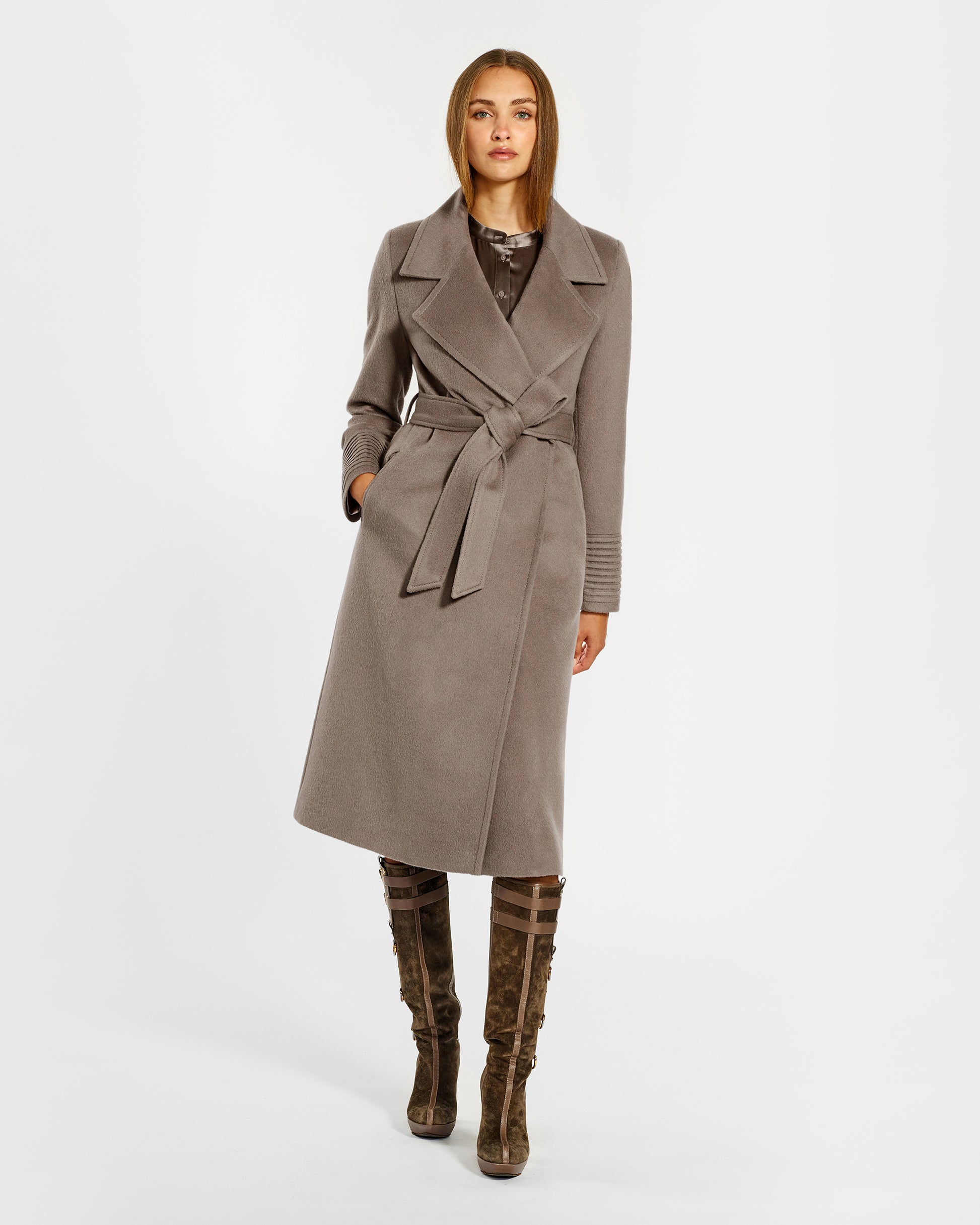 Front view of model wearing a Sentaler warm taupe long coat made of baby alpaca wool, with a wide notched collar, worn belted.