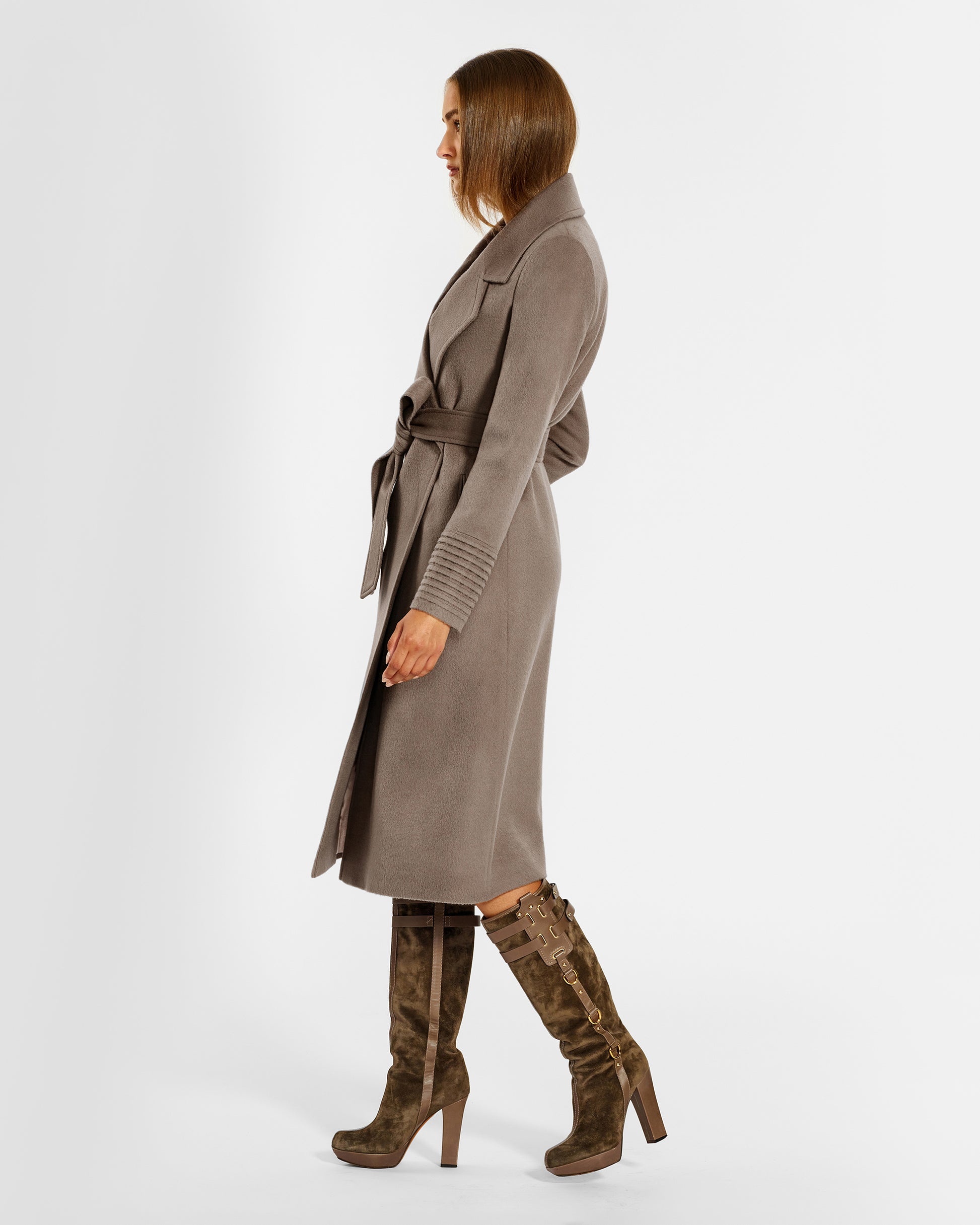 Side view of model wearing a Sentaler warm taupe long coat made of baby alpaca wool, with a wide notched collar, worn belted.