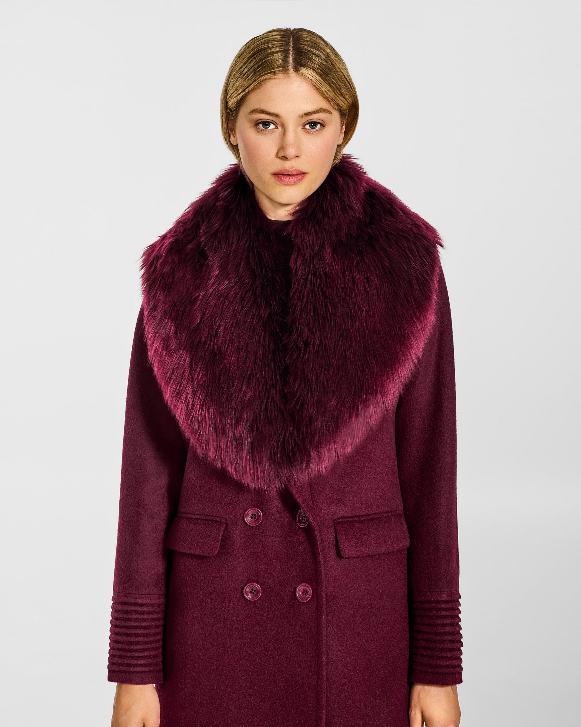 Front view of model wearing a Sentaler cherry lacquer double breasted maxi coat made of baby alpaca wool, with a peak collar, worn with alpaca shearling collar, buttoned.