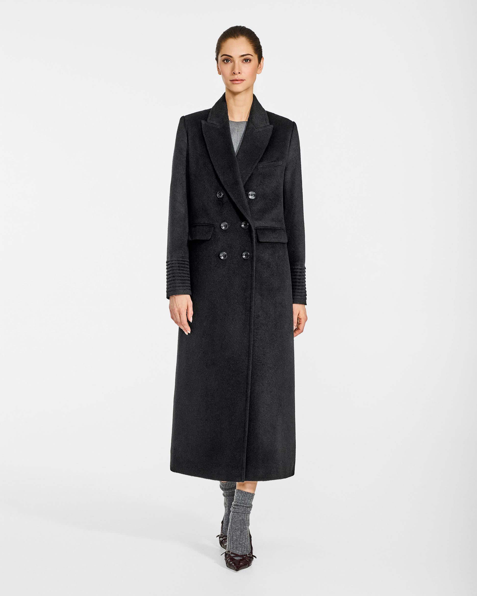 Front view of model wearing a Sentaler black double breasted maxi coat made of baby alpaca wool, with a peak collar, worn buttoned.