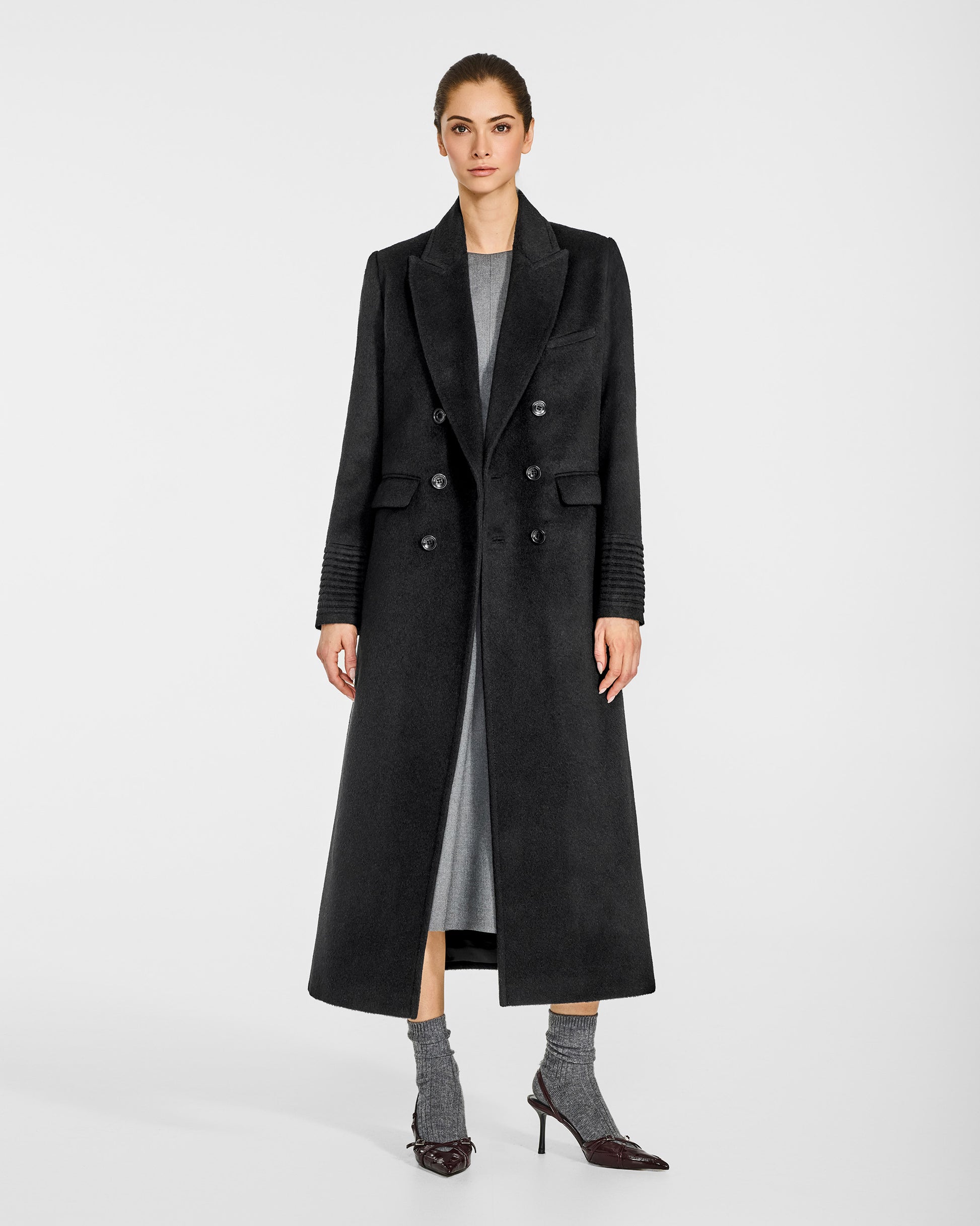 Front view of model wearing a Sentaler black double breasted maxi coat made of baby alpaca wool, with a peak collar, worn open.
