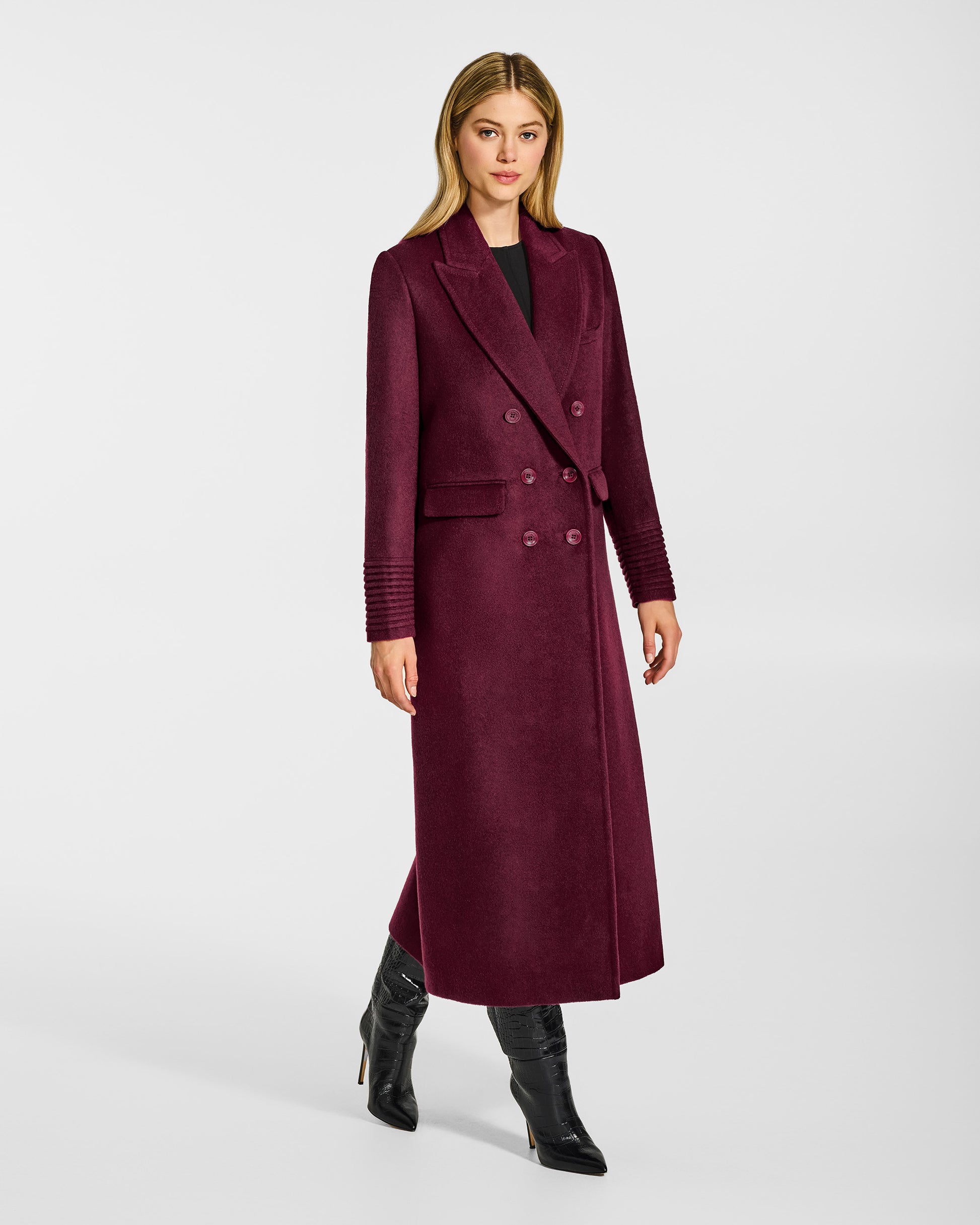 Side view of model wearing a Sentaler cherry lacquer double breasted maxi coat made of baby alpaca wool, with a peak collar, worn buttoned.