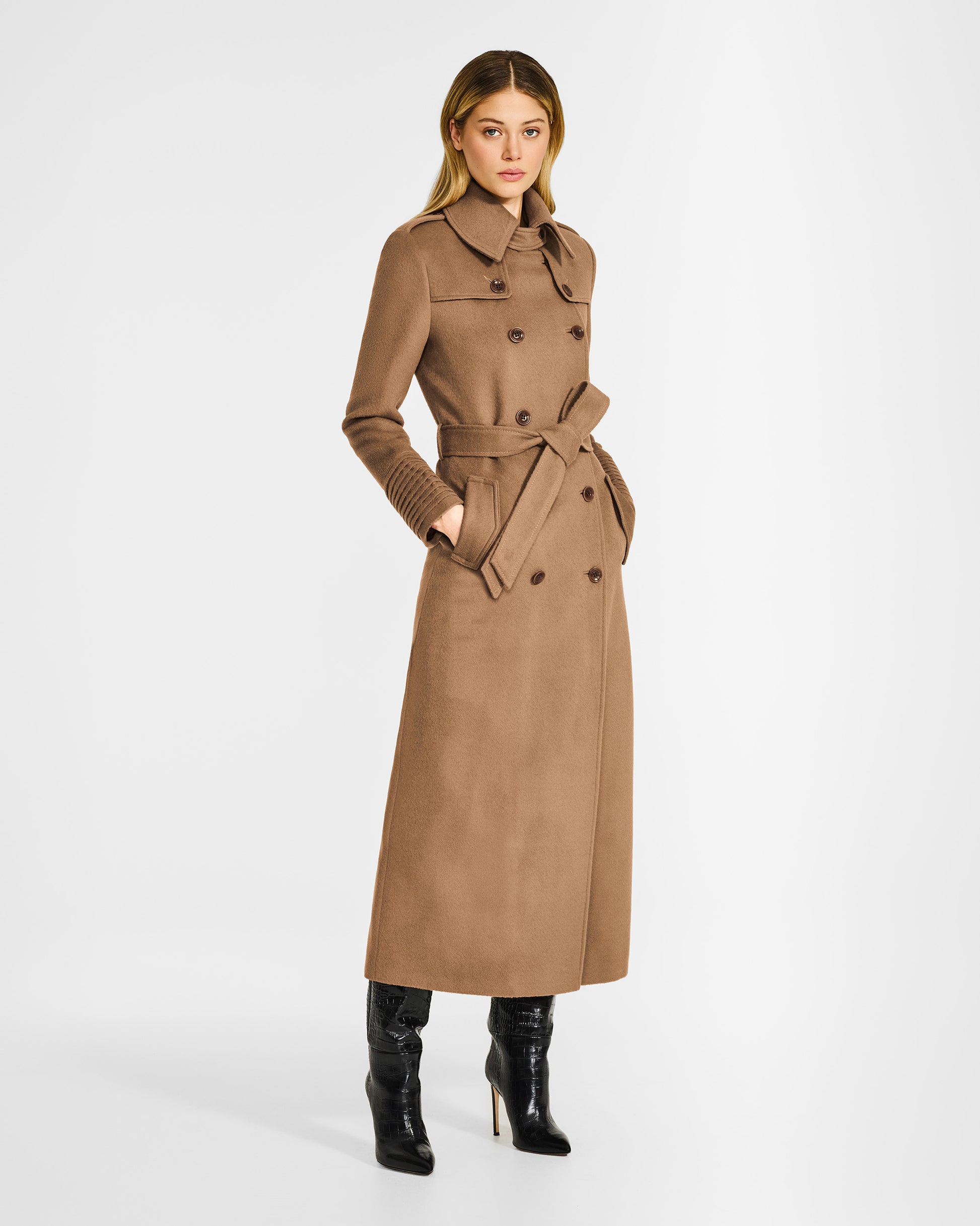 Side view of model in Sentaler maxi dark camel trench coat in baby alpaca wool, buttoned and belted.