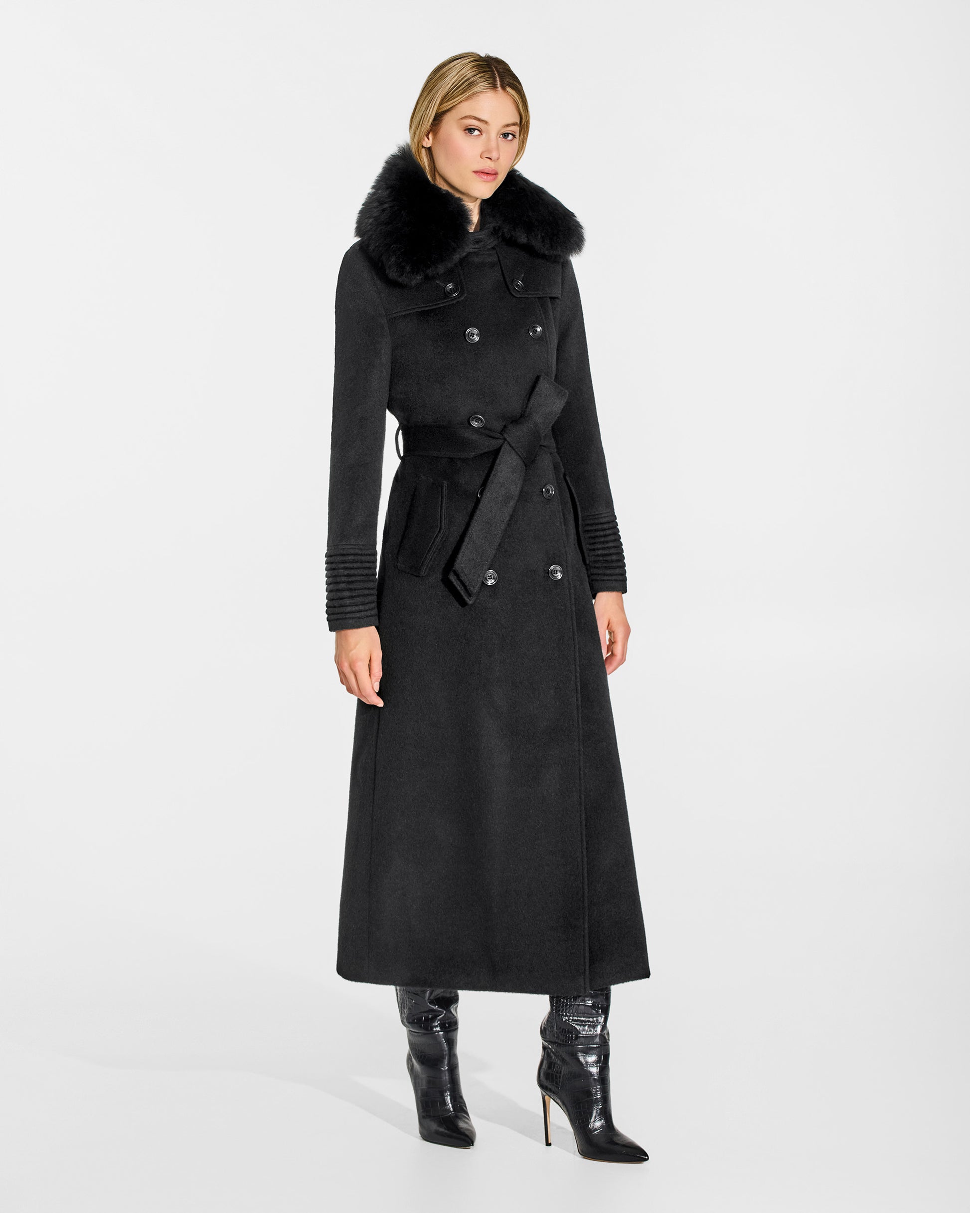 Side view of model in Sentaler maxi black trench coat made of baby alpaca wool with shearling collar, belted