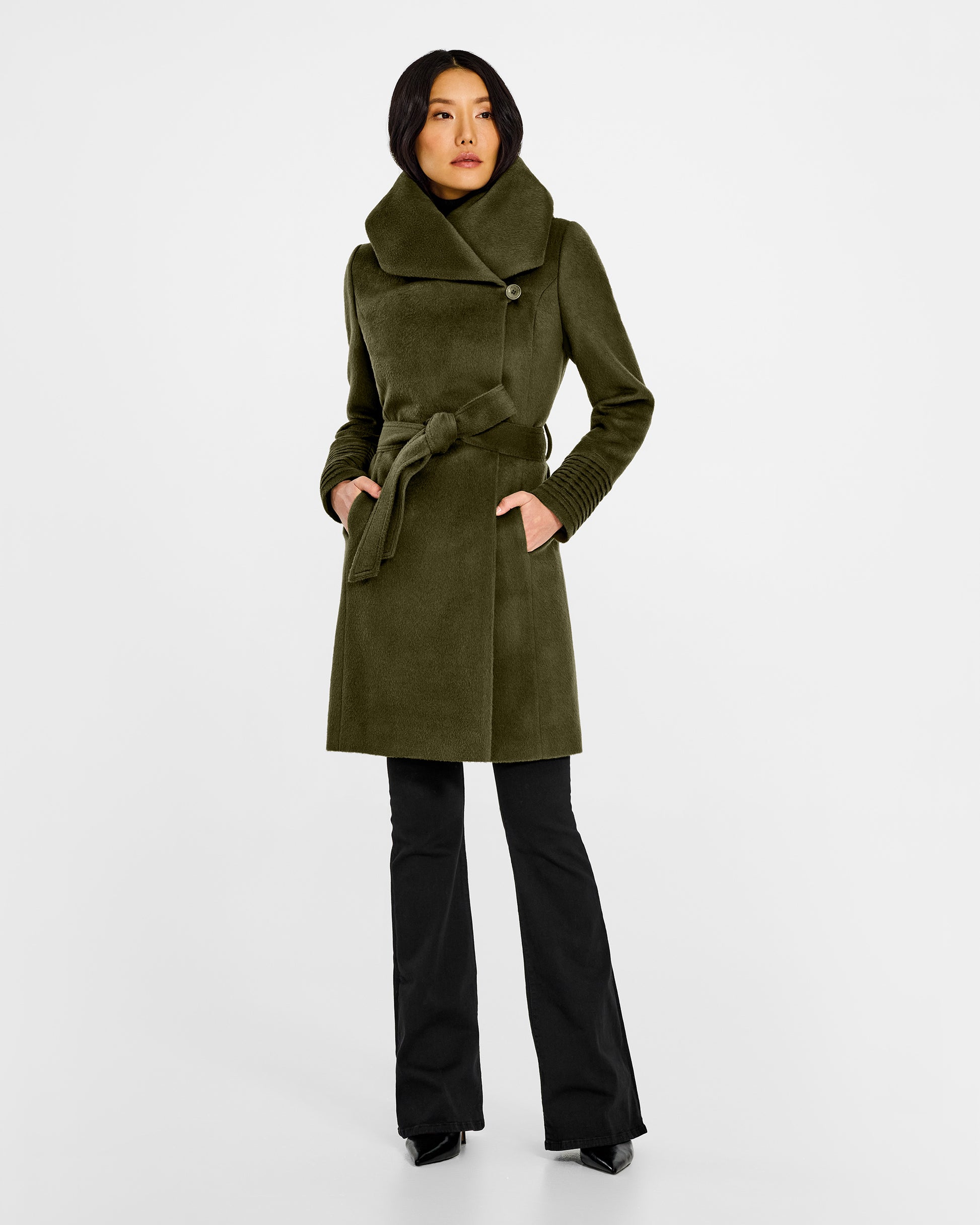 Front view of model wearing a Sentaler mid length olive green coat made of baby alpaca wool, with a hooded collar, worn belted.