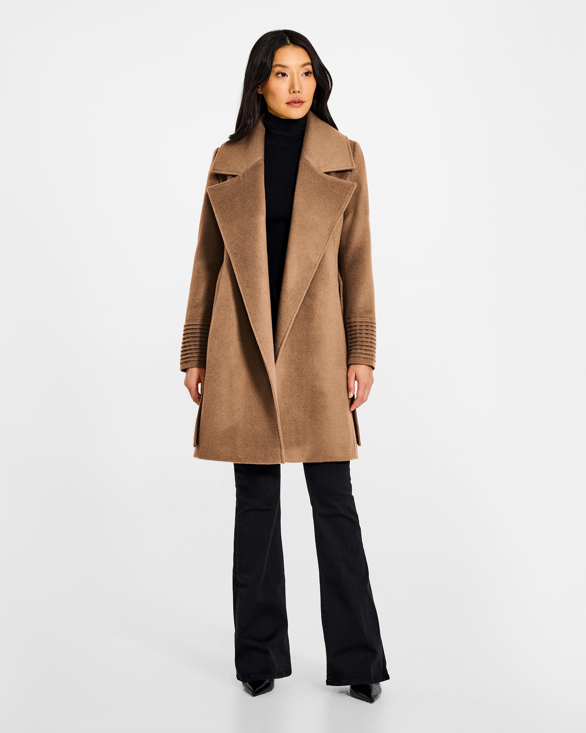 Front view of model wearing a Sentaler mid length dark camel coat made of baby alpaca wool, with a large notched collar, worn open.