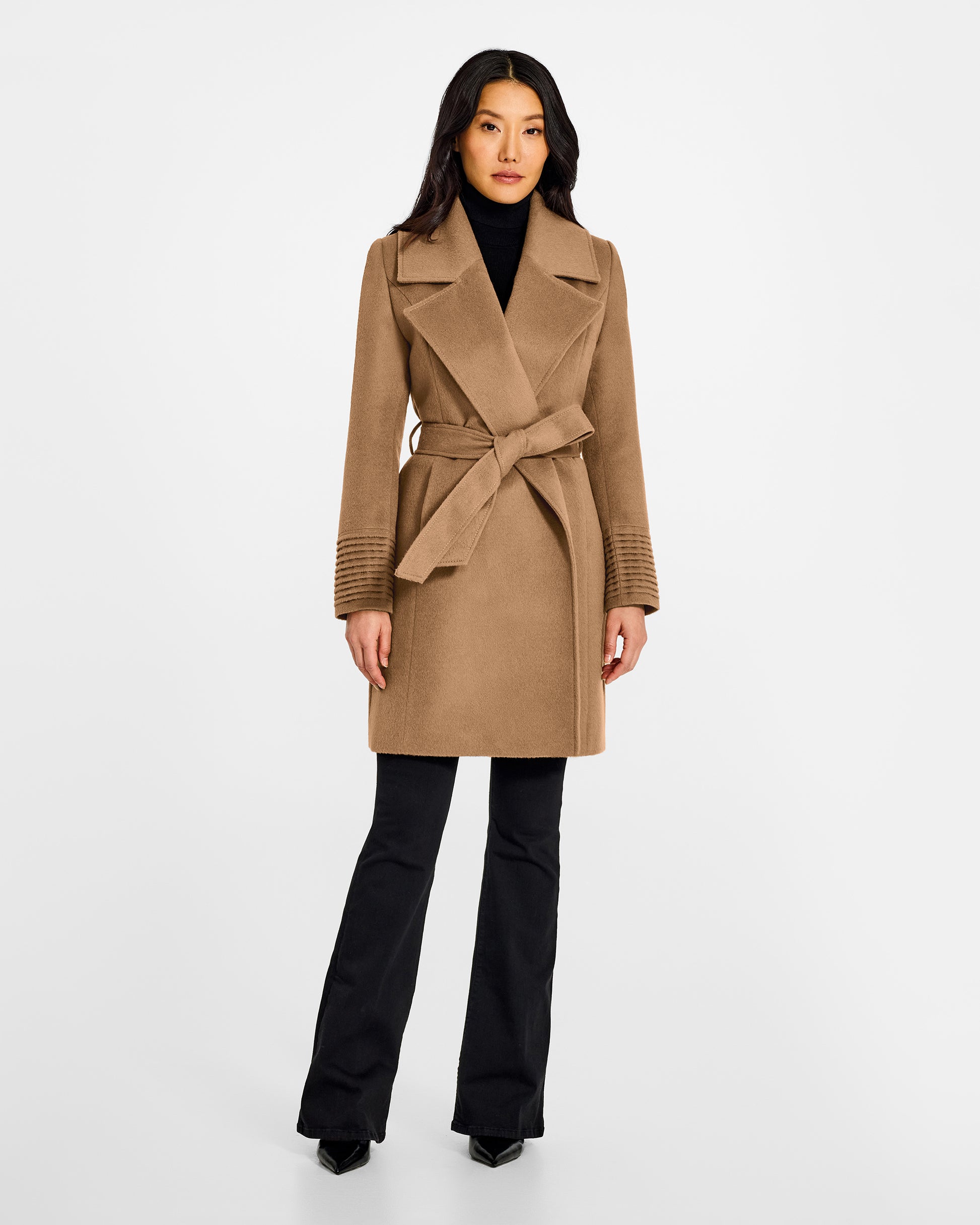 Front view of model wearing a Sentaler mid length dark camel coat made of baby alpaca wool, with a large notched collar, worn belted.