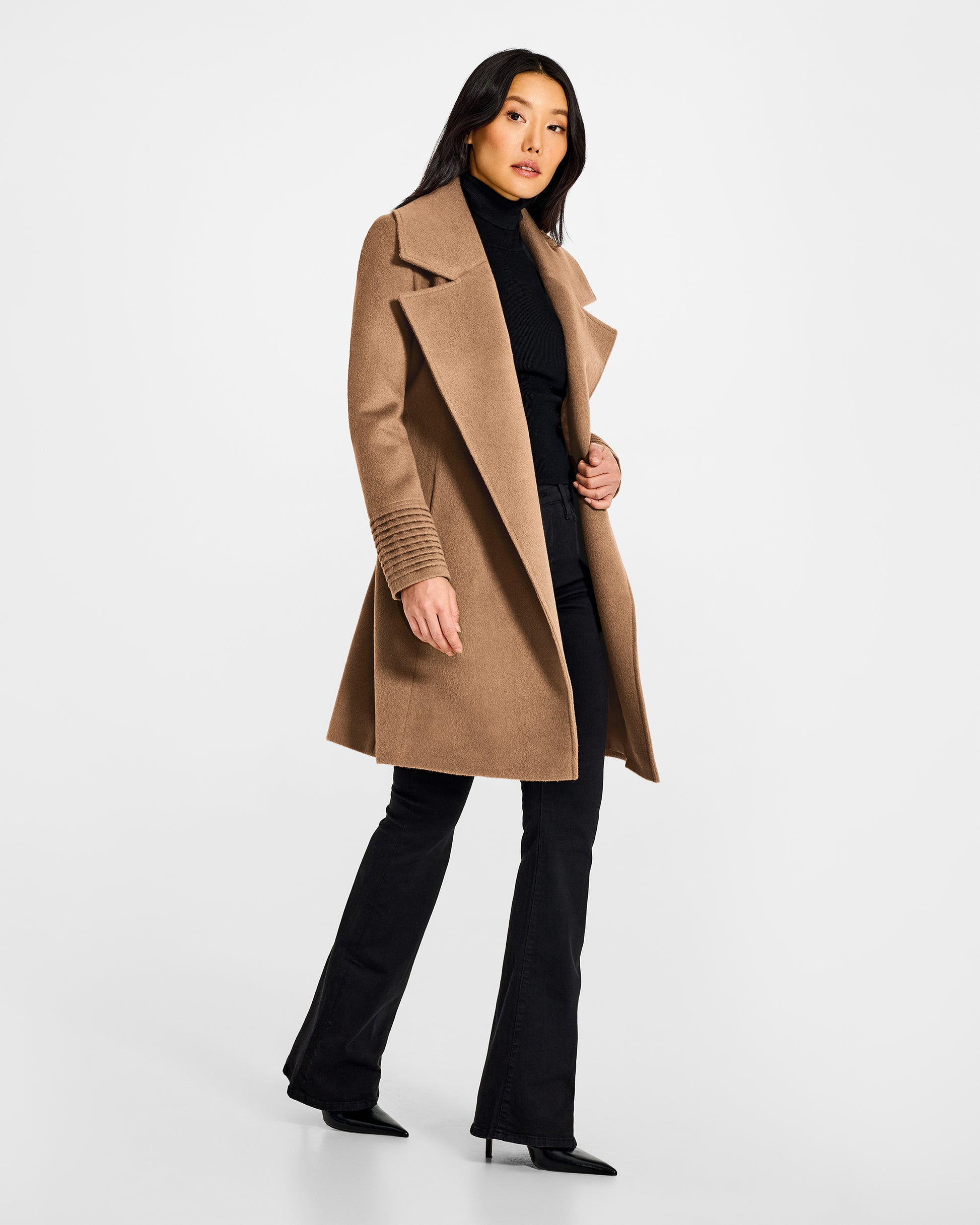 Side view of model wearing a Sentaler mid length dark camel coat made of baby alpaca wool, with a large notched collar, worn open.