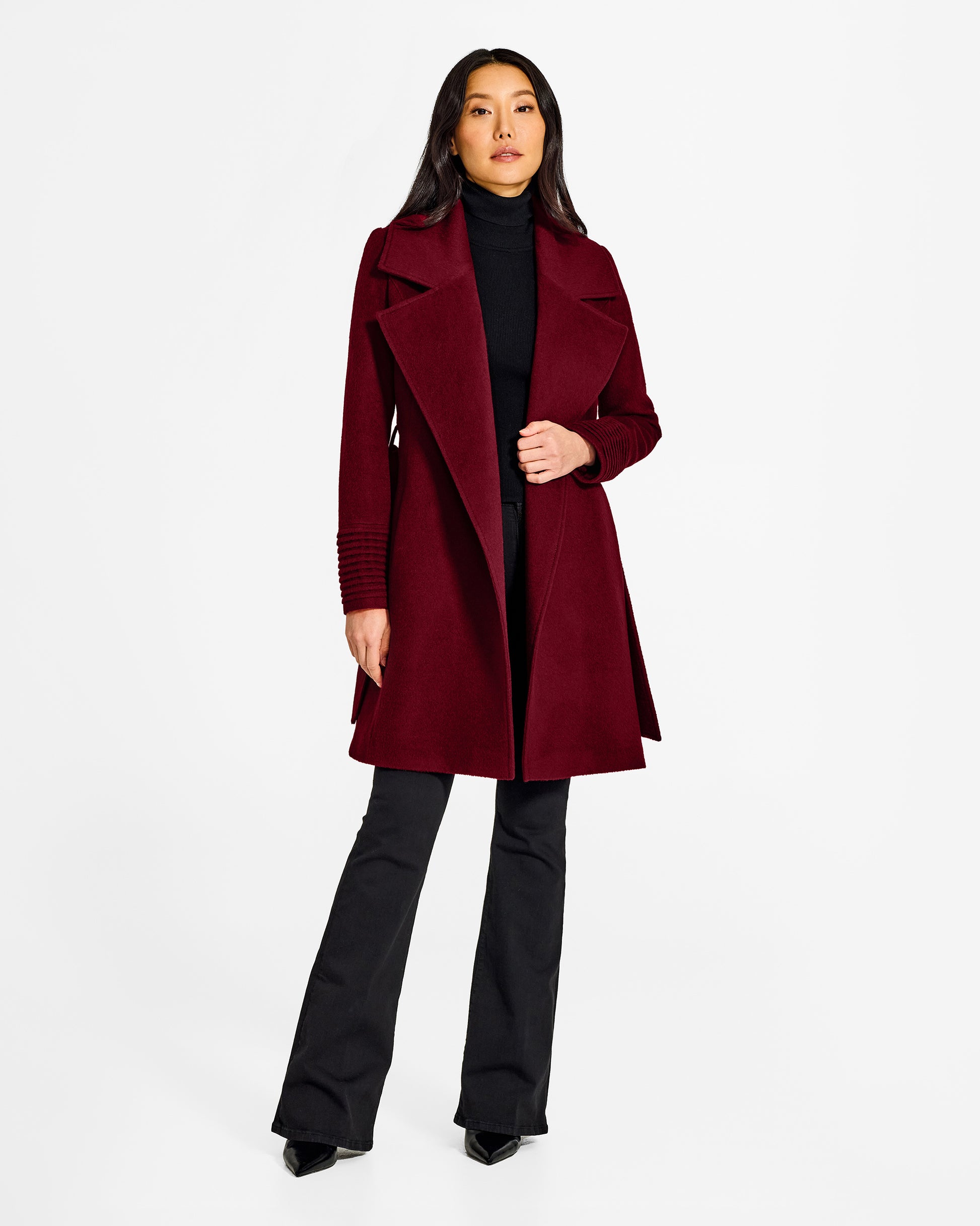 Front view of model wearing a Sentaler mid length garnet red coat made of baby alpaca wool, with a large notched collar, worn open.