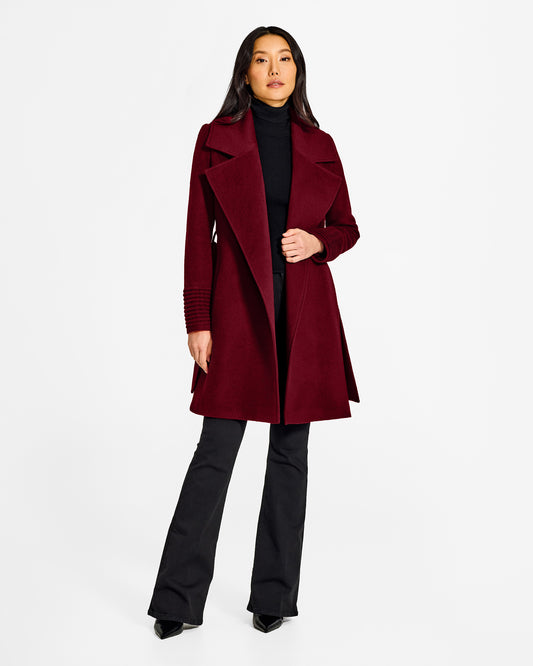 Front view of model wearing a Sentaler mid length garnet red coat made of baby alpaca wool, with a large notched collar, worn open.