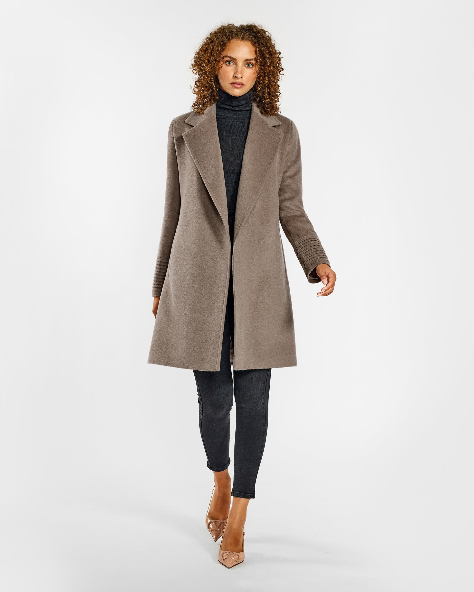 Front view of model wearing a Sentaler mid length warm taupe coat made of baby alpaca wool, with a notched collar, worn open.