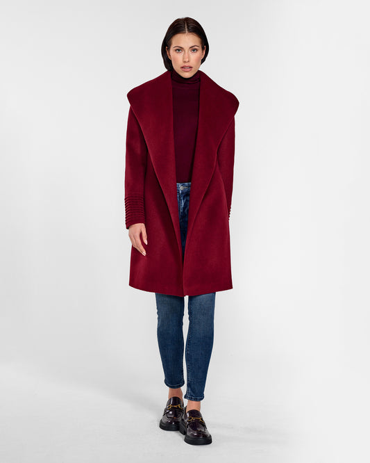 Front view of model wearing a Sentaler mid length garnet red coat made of baby alpaca wool, with a shawl collar, worn open.