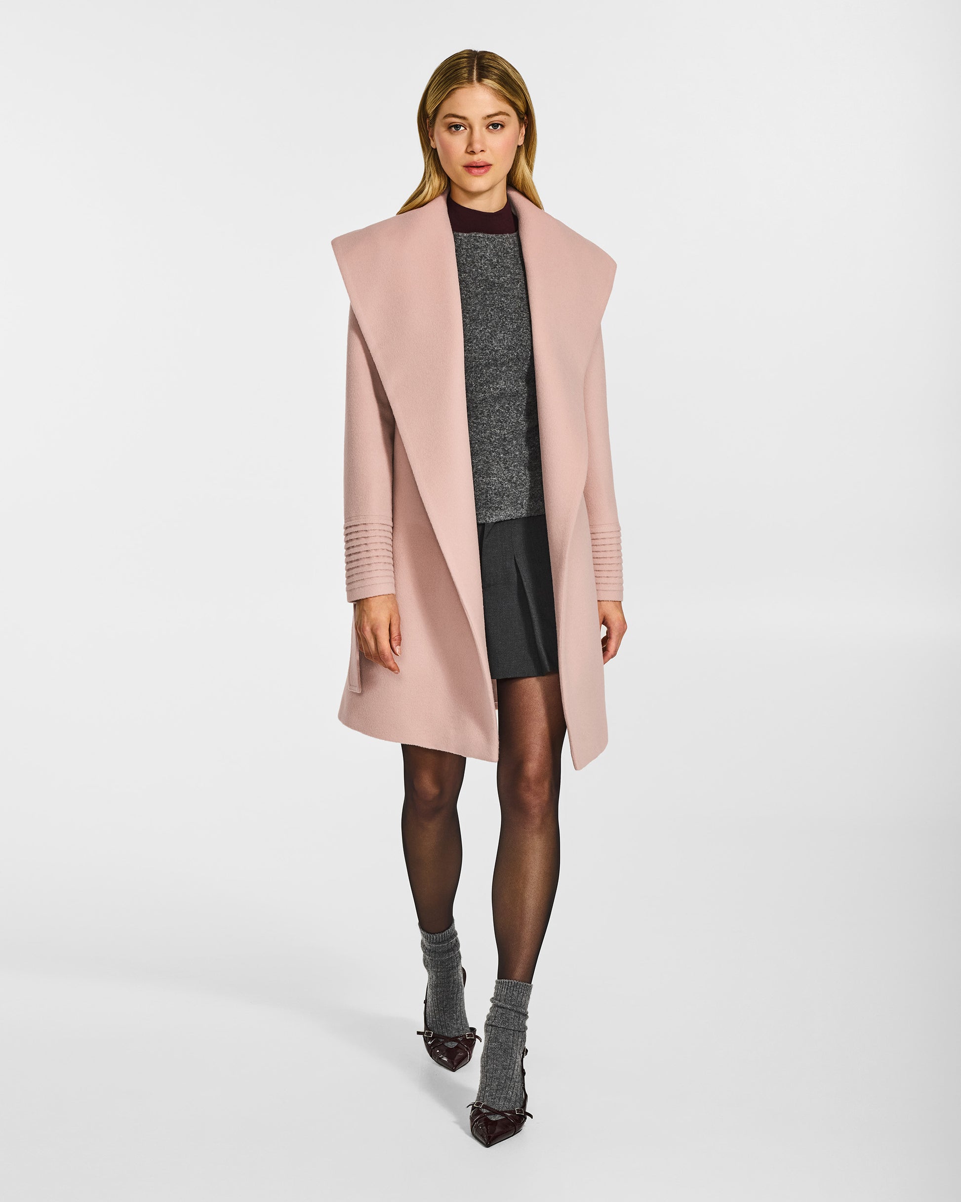 Front view of model wearing a Sentaler mid length blush pink coat made of baby alpaca wool, with a shawl collar, worn open.