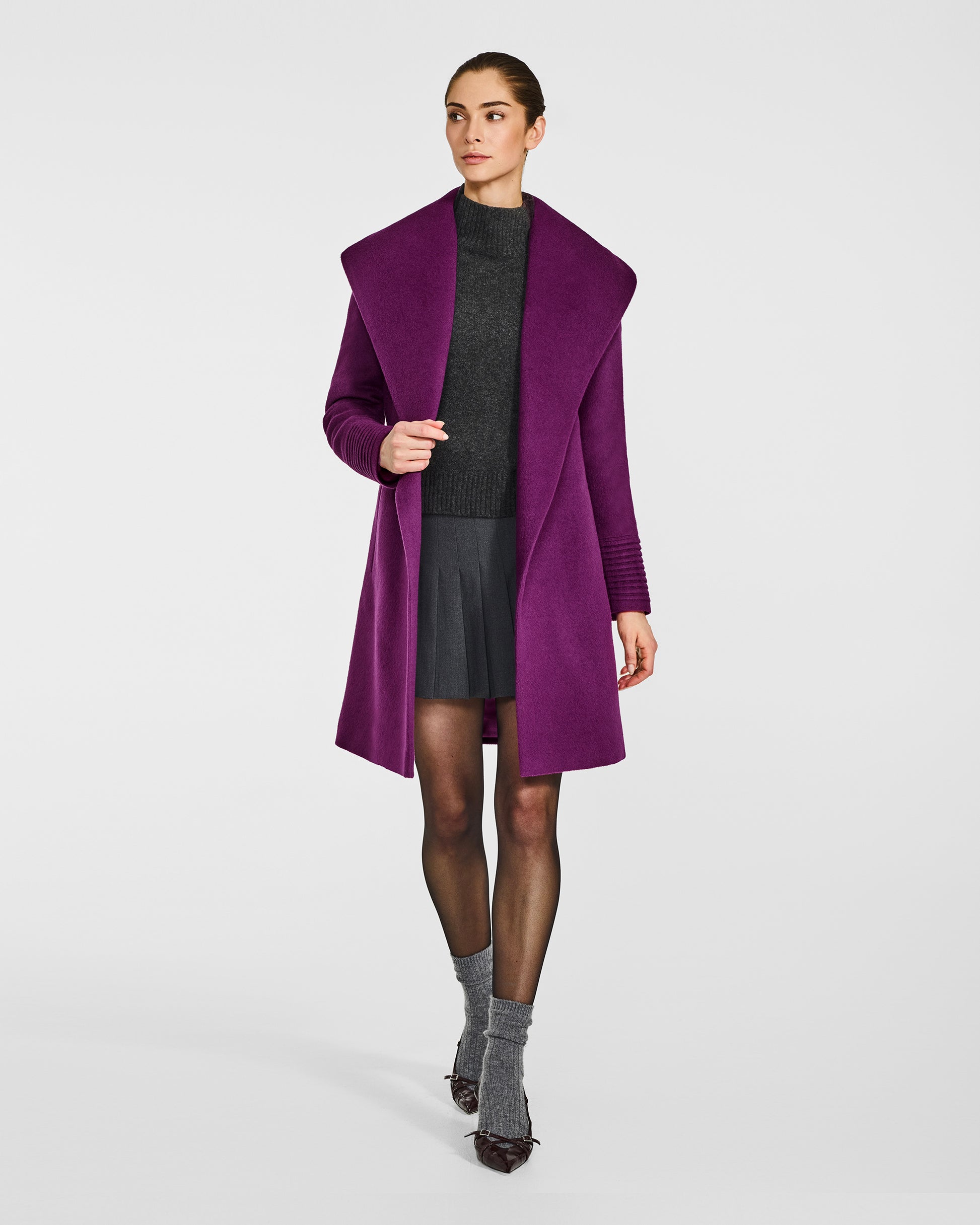 Front view of model wearing a Sentaler mid length dark mulberry purple coat made of baby alpaca wool, with a shawl collar, worn open.
