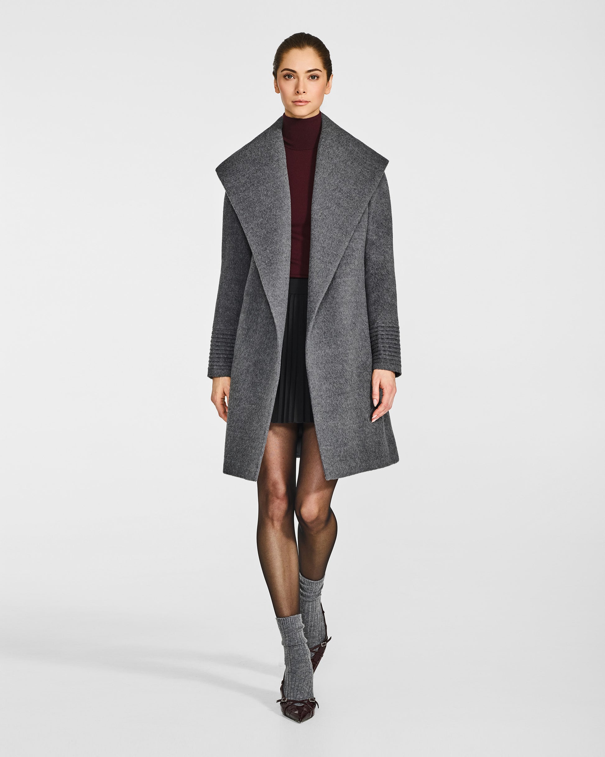 Front view of model wearing a Sentaler mid length grey mélange coat made of baby alpaca wool, with a shawl collar, worn open.