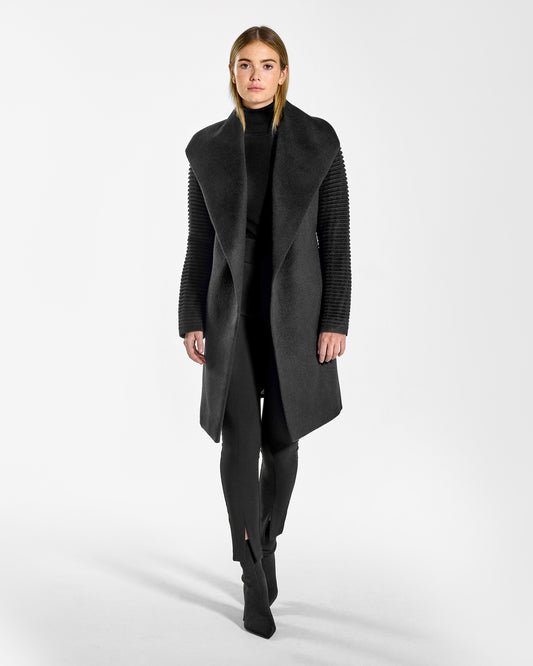 Front view of model wearing a Sentaler mid length black wrap coat made of baby alpaca wool, with ribbed sleeves, worn open.