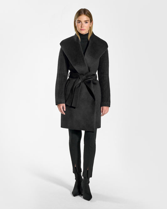 Front view of model wearing a Sentaler mid length black wrap coat made of baby alpaca wool, with ribbed sleeves, worn belted.
