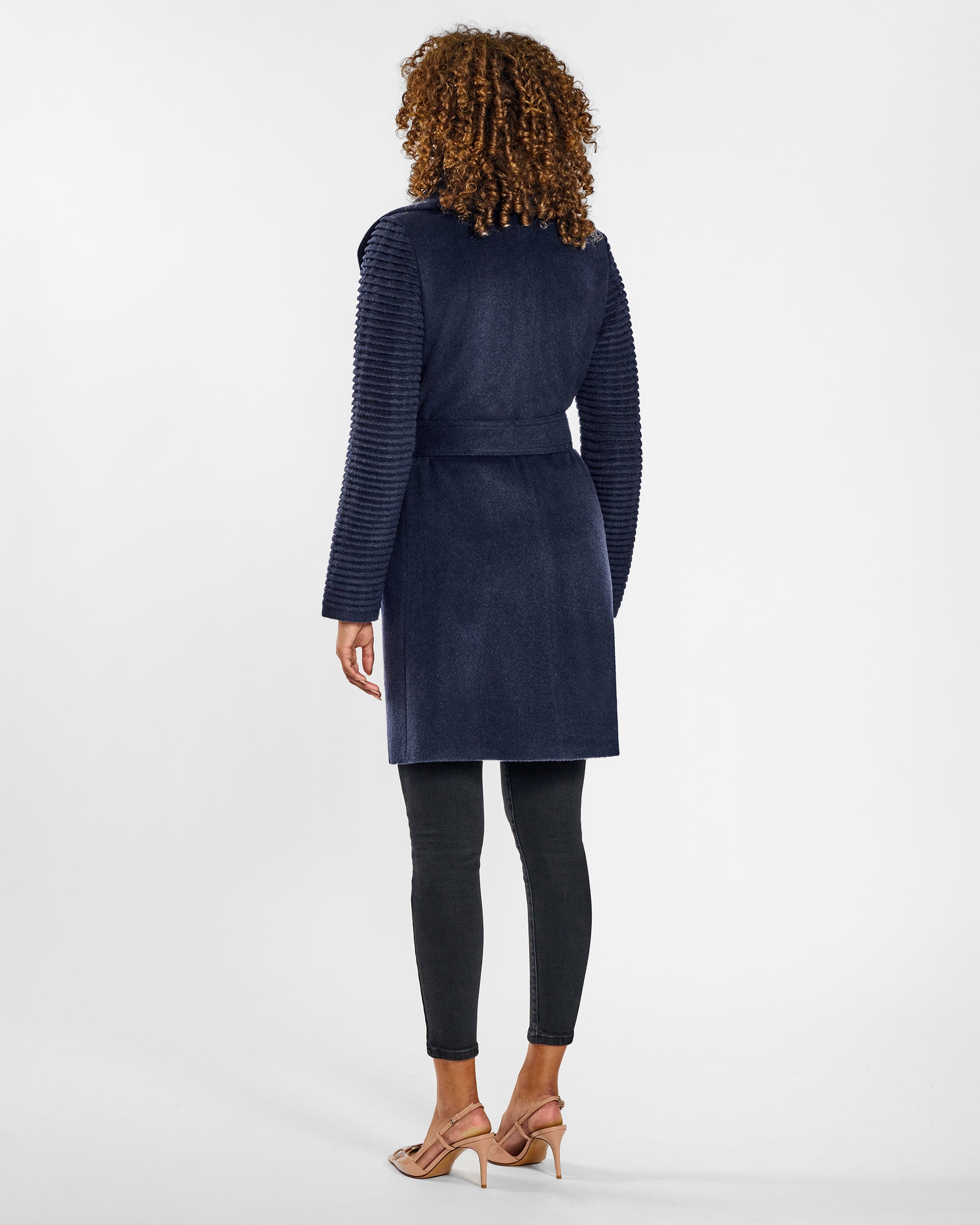 Back view of model wearing a Sentaler mid length deep navy wrap coat made of baby alpaca wool, with ribbed sleeves, worn belted. 