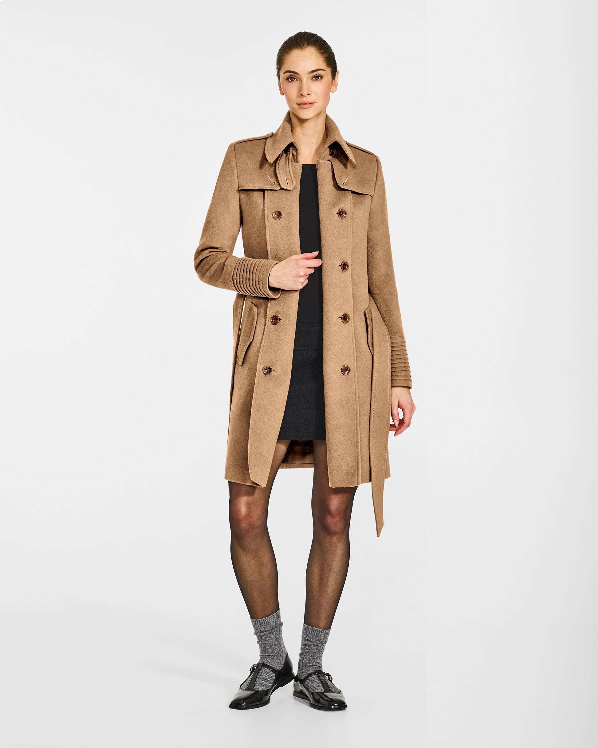 Front view of model wearing a Sentaler mid length dark camel trench coat made of baby alpaca wool, with a spread collar, worn open.