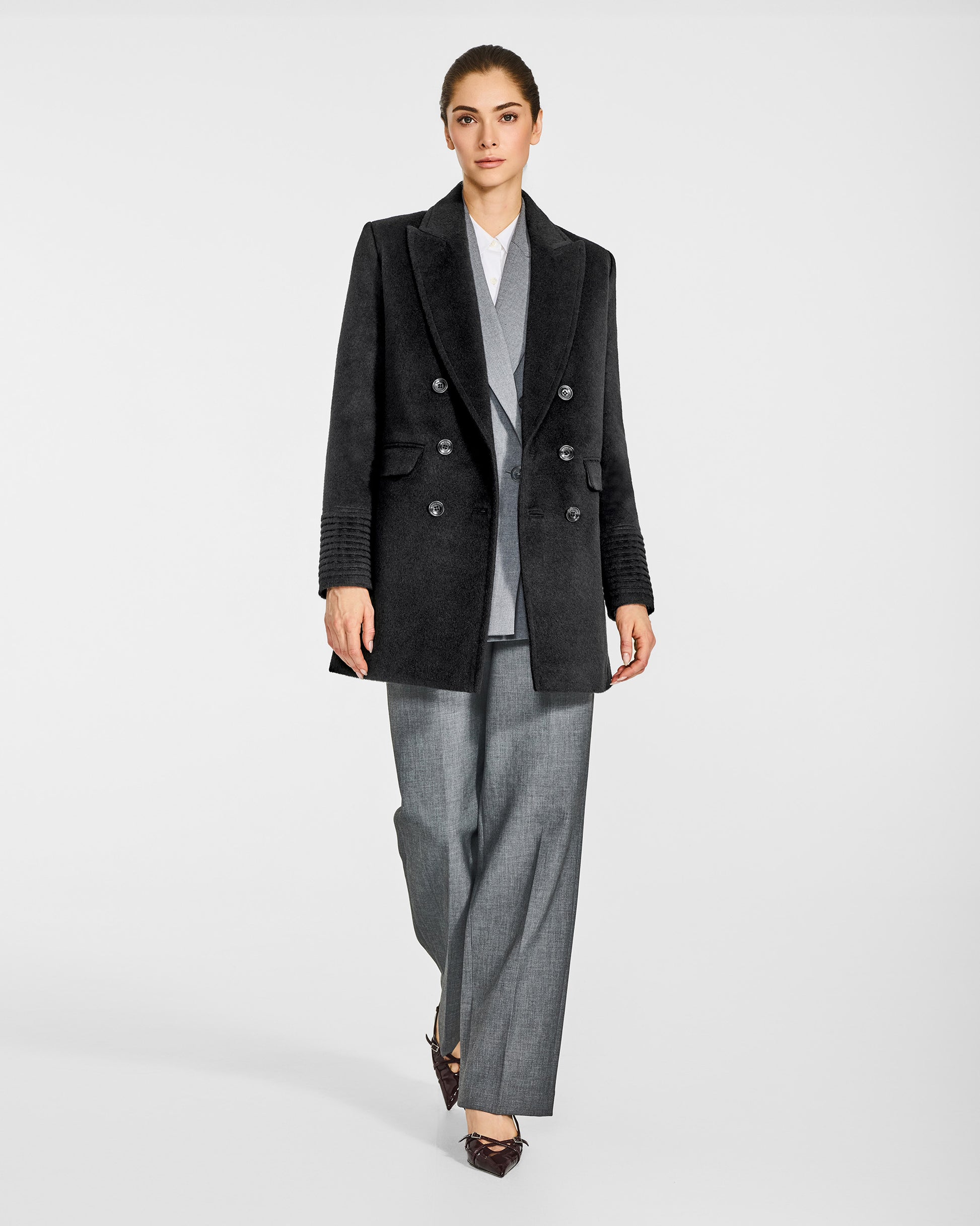 Front view of model in Sentaler black topcoat with peak collar in baby alpaca wool, open.