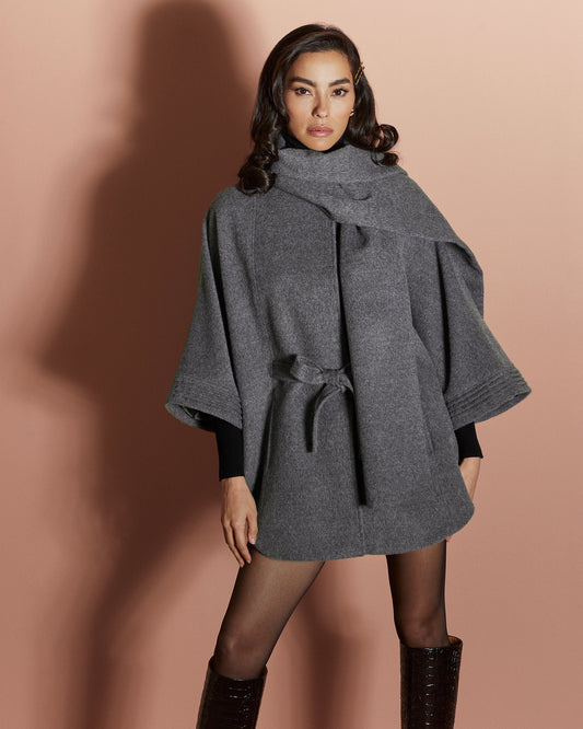 Front view of model wearing a Sentaler grey mélange cape made of baby alpaca wool, with a scarf collar, worn belted.