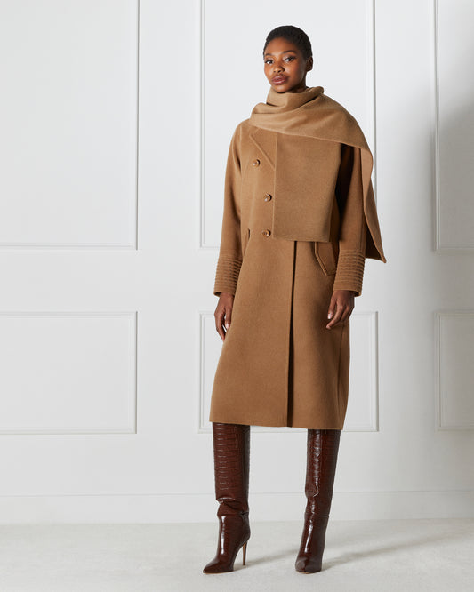 Front view of model wearing a Sentaler dark camel double breasted coat made of baby alpaca wool with a notched collar, worn with fabric scarf, buttoned.